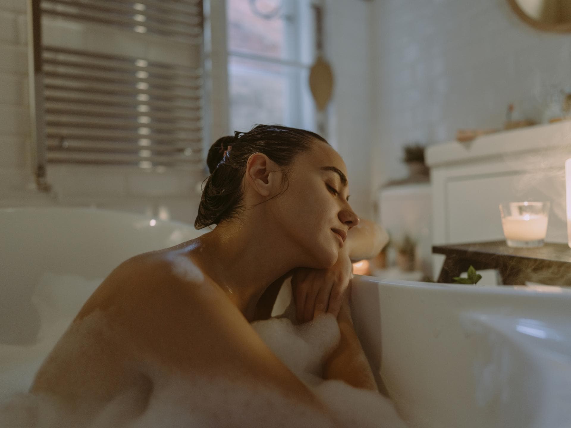 Eine Frau, die in der Badewanne sitzt und die Augen schließt. 