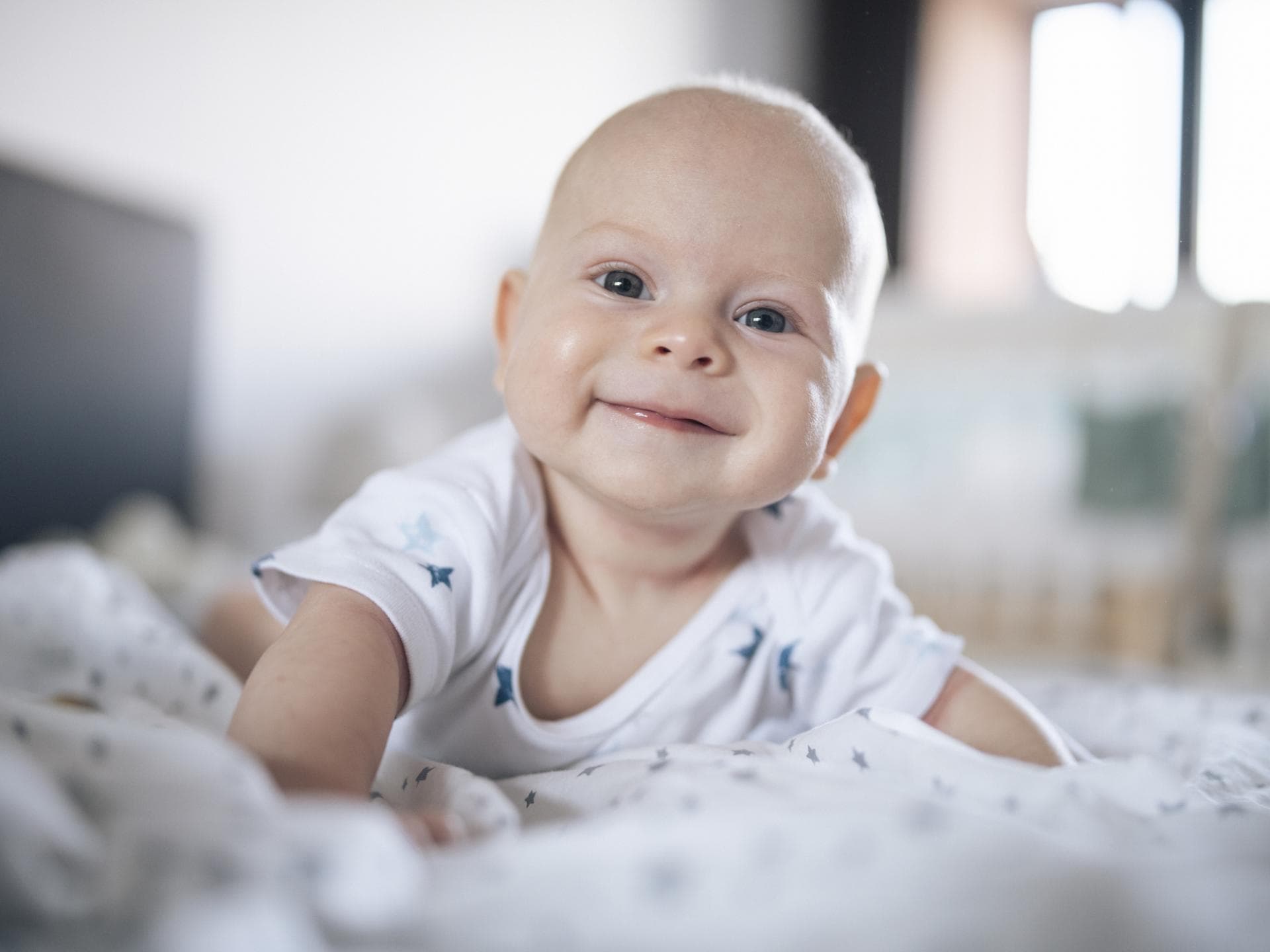 Lächelndes Baby liegt auf dem Bauch.