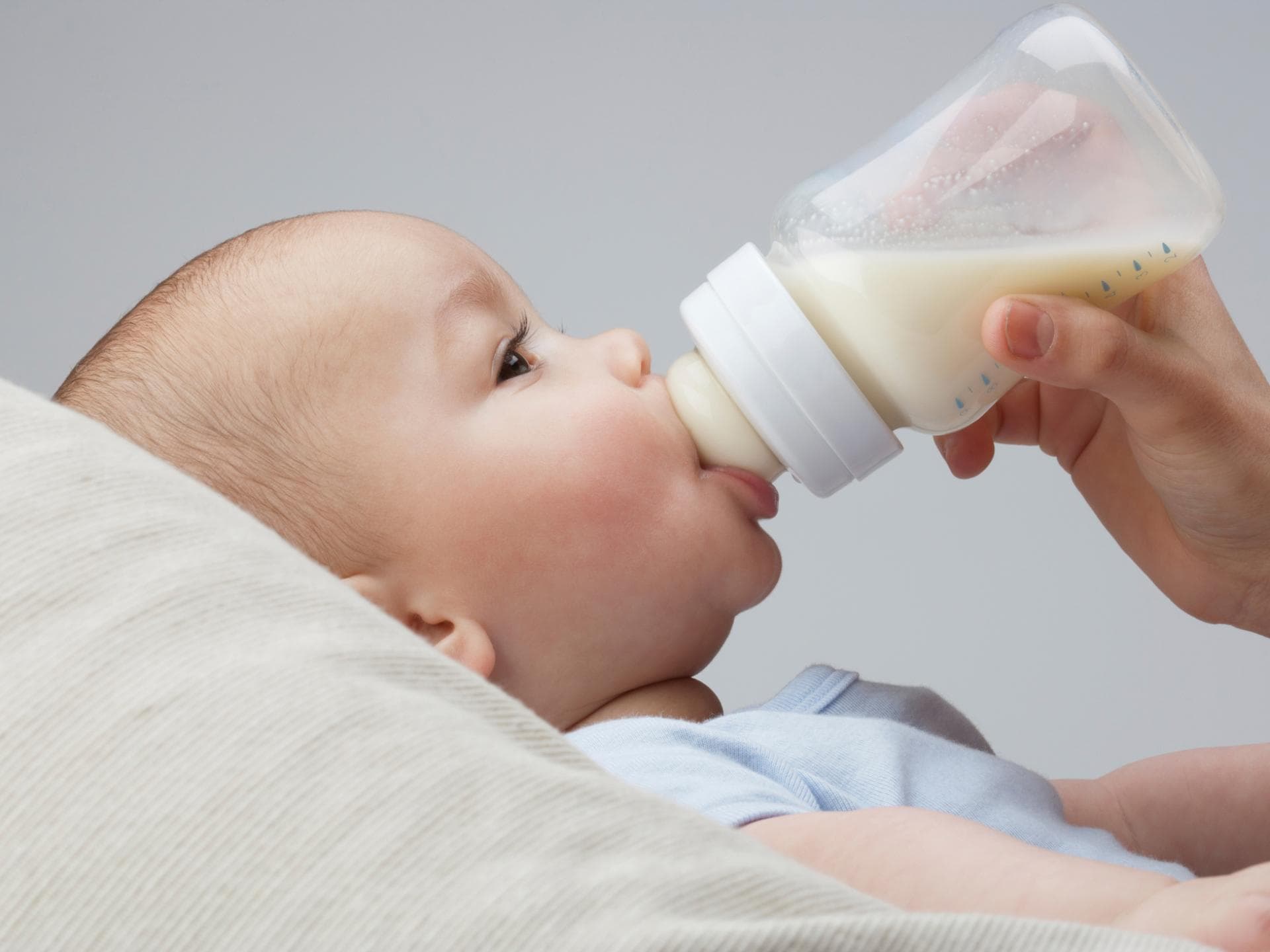 Ärzte raten davon ab, Pre-Milch selbst herzustellen. Baby trinkt Milch aus der Flasche.