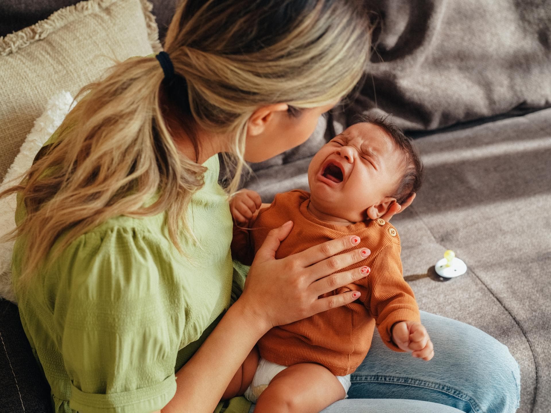 Mama versucht, ihr Neugeborenes zu beruhigen – manchmal gar nicht so einfach. Mama versucht, ihr Neugeborenes zu beruhigen.