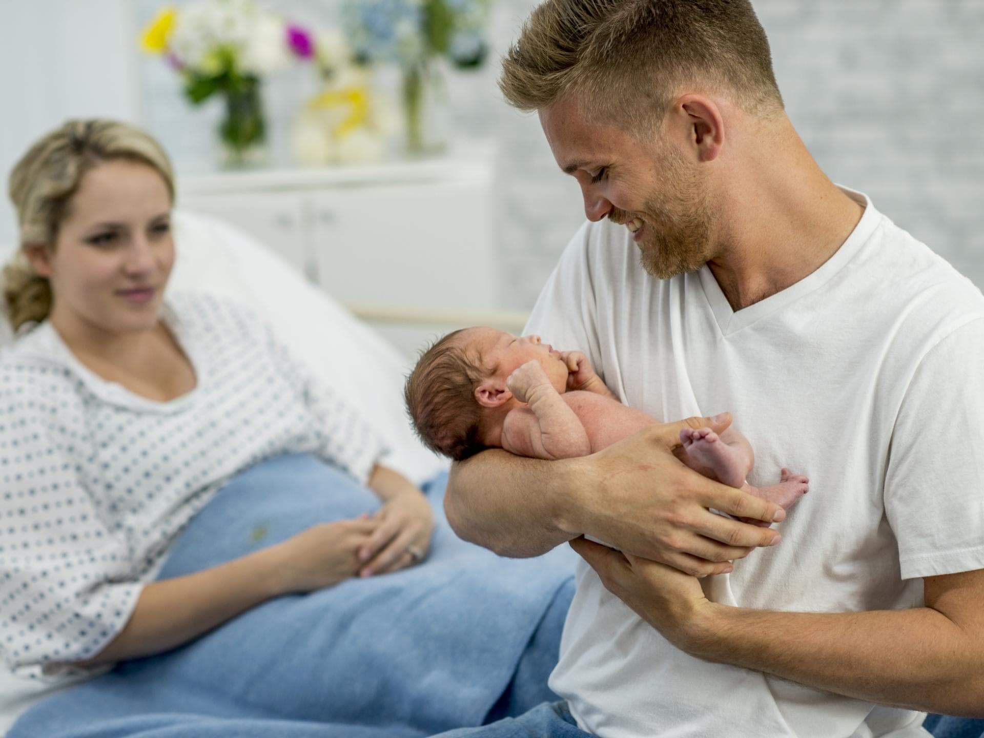 Im Kreißsaal sind für die Unterstützung ihrer Frau da. Vater hält sein neugeborenes Baby im Arm.