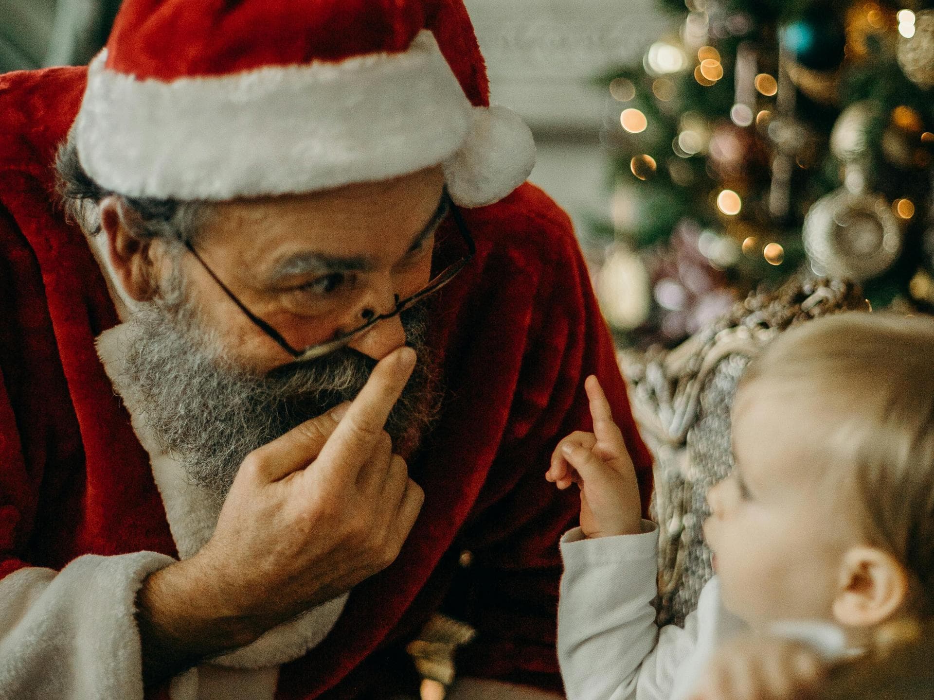 Weihnachtsmann spricht mit kleinem Kind.