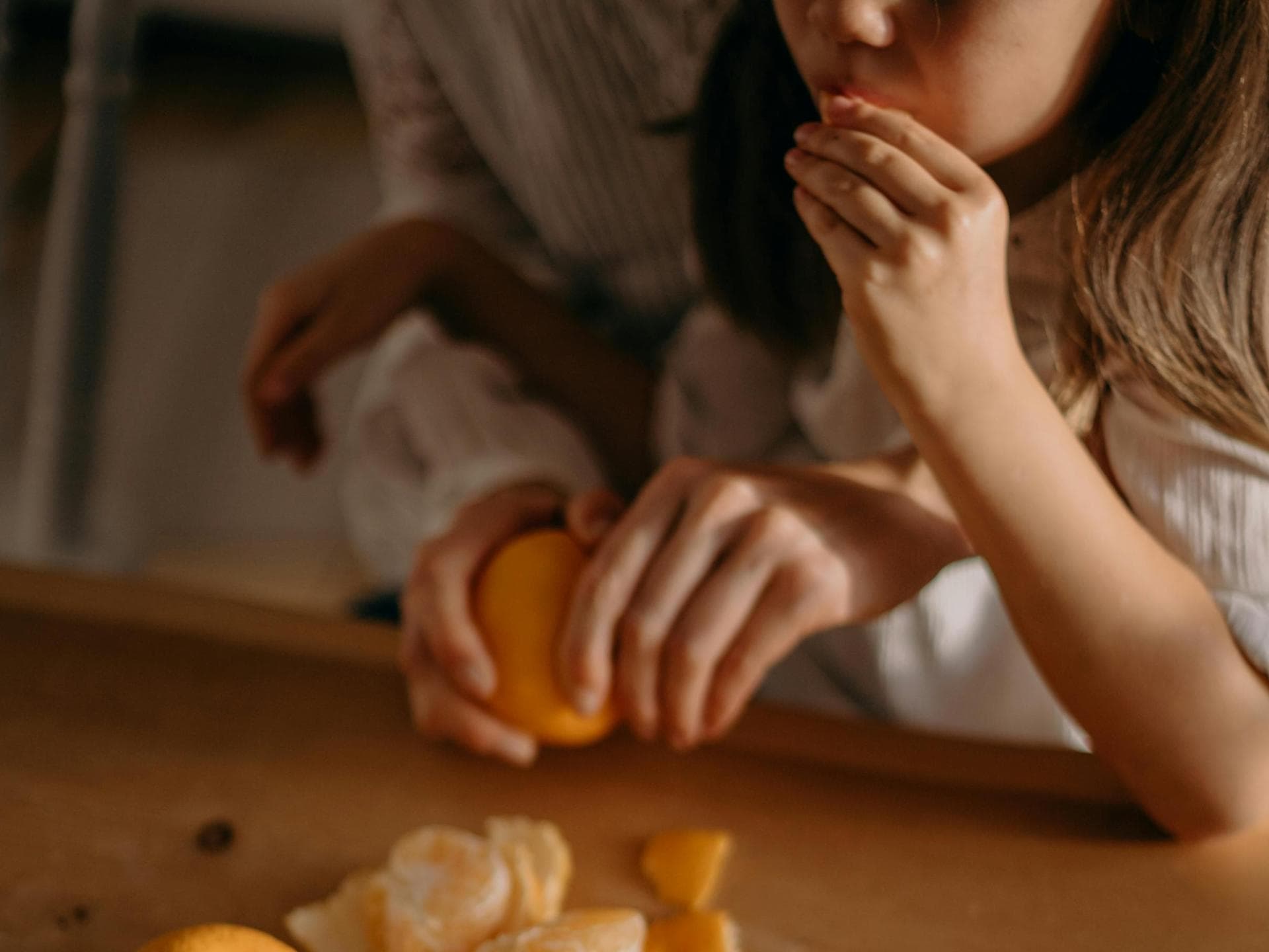 Mädchen isst Mandarine, Mutter schält sie.
