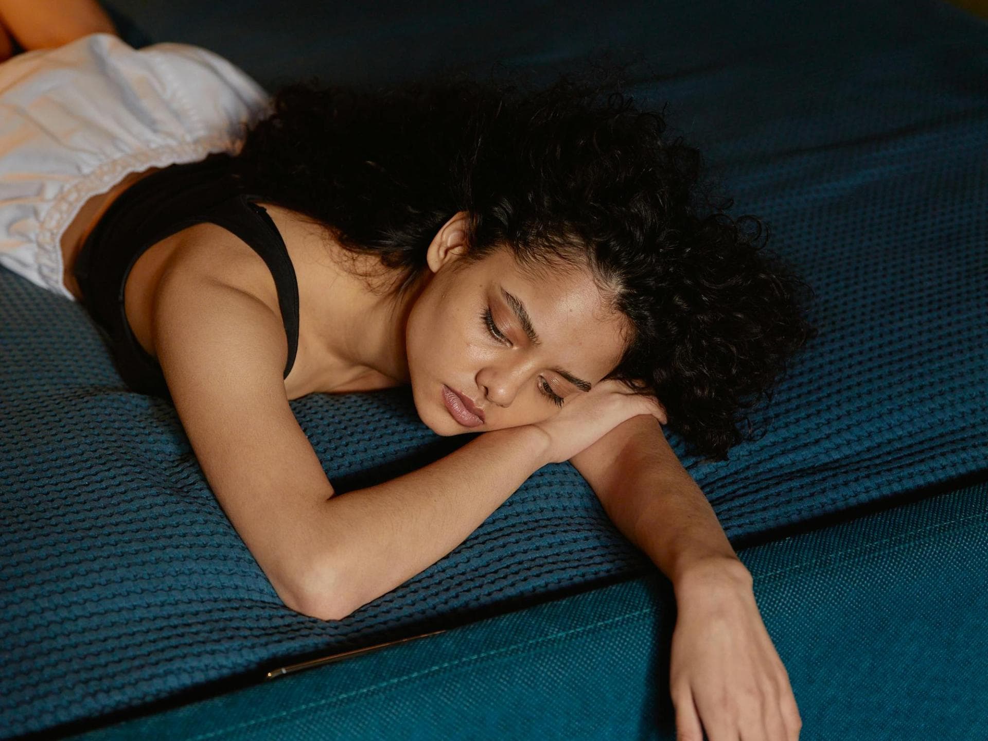 Teenager liegt nachdenklich auf dem Bett.