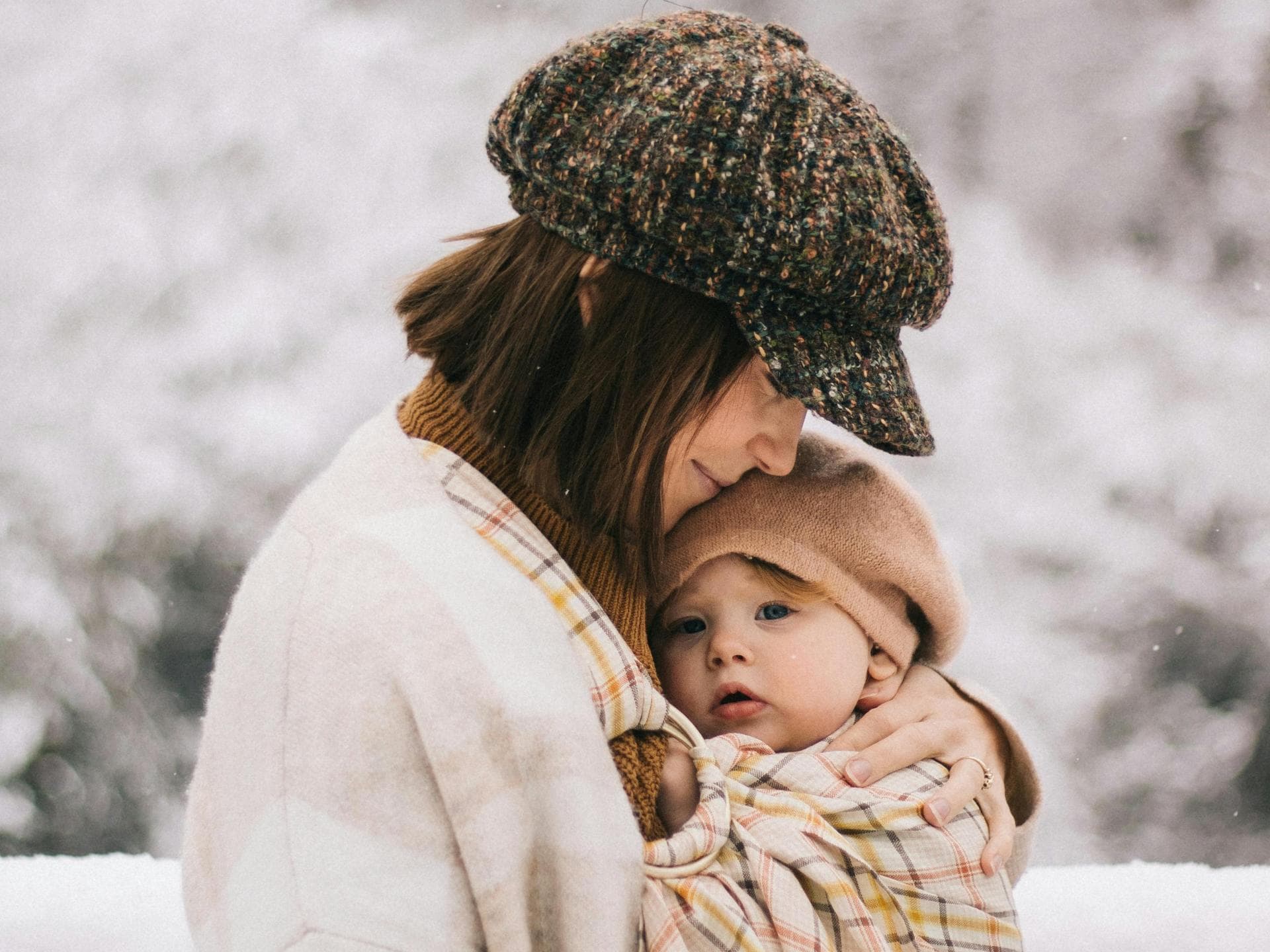 Mama kuschelt im Winter mit Baby