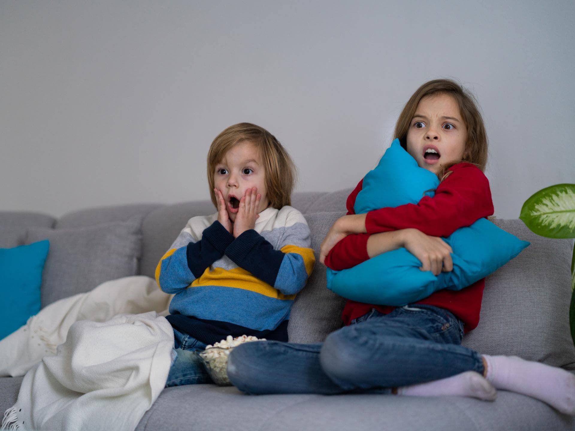 Zwei kleine Kinder fürchten sich vor dem Fernseher. 