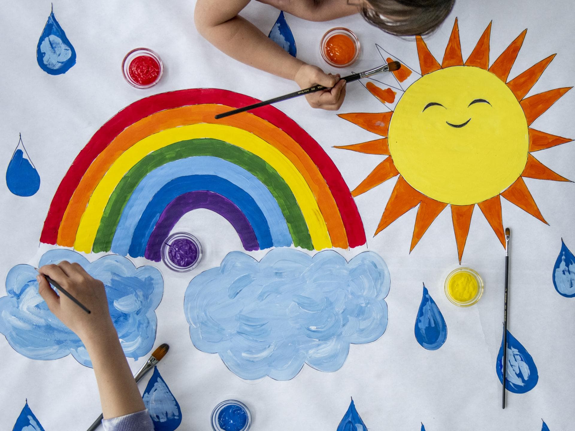 Kinder malen Regenbogen.