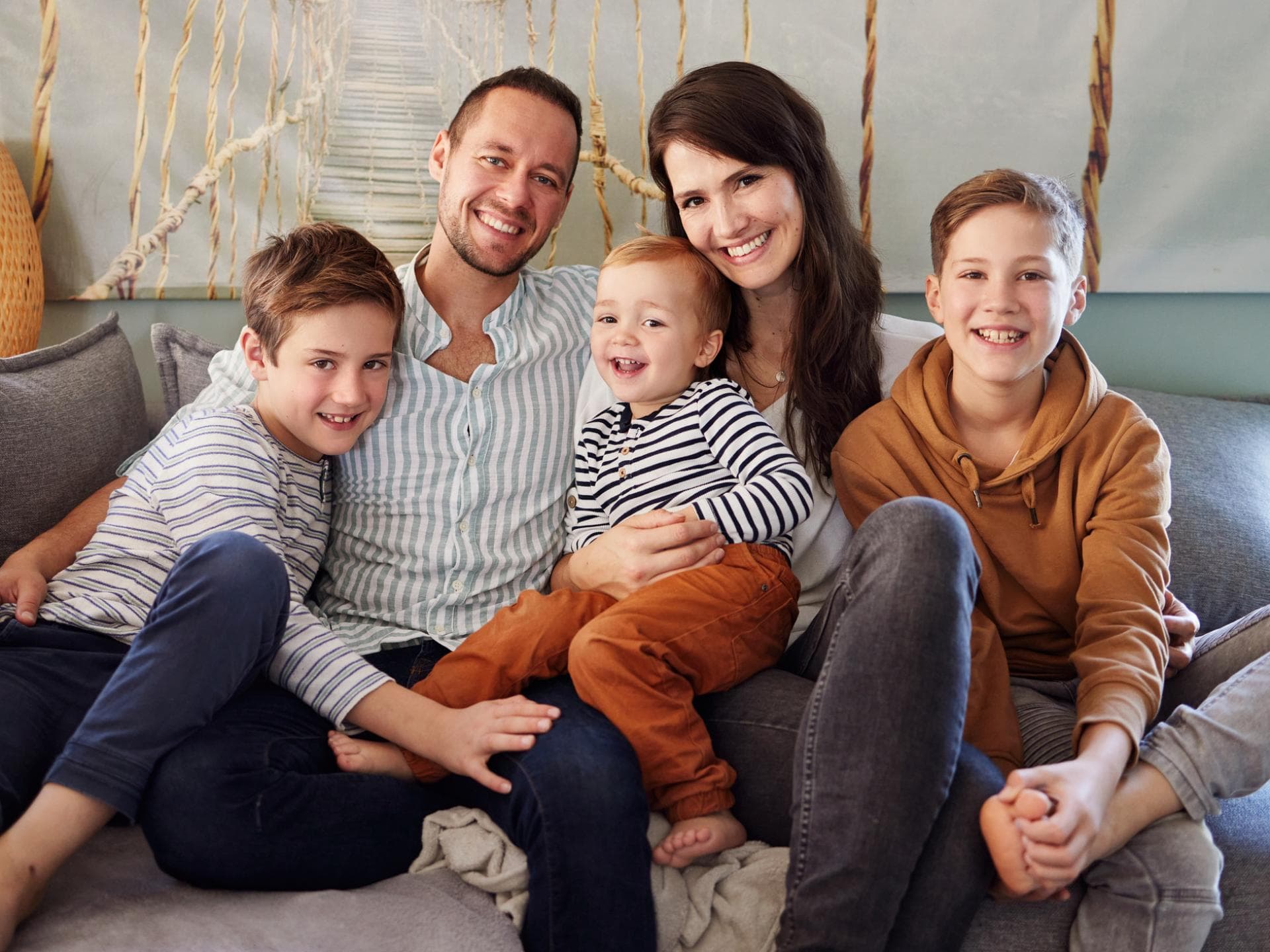 Für Familien gibt es 2025 einige Gesetzesänderungen. Familie mit drei Kindern sitzt auf dem Sofa.