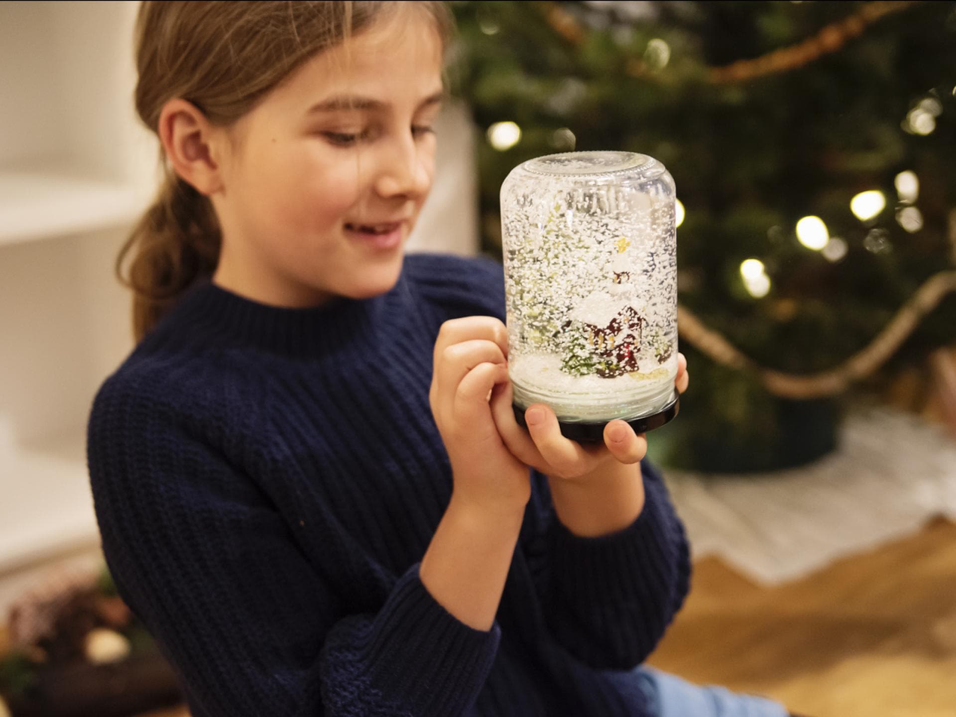 Mädchen hält selbstgebastelte Schneekugel in der Hand.