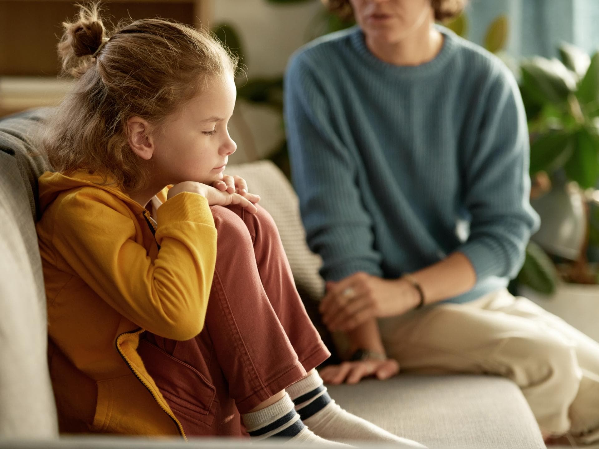 Über Ängste sollte man sprechen. Mutter spricht ernst mit ihrem Kind auf dem Sofa.