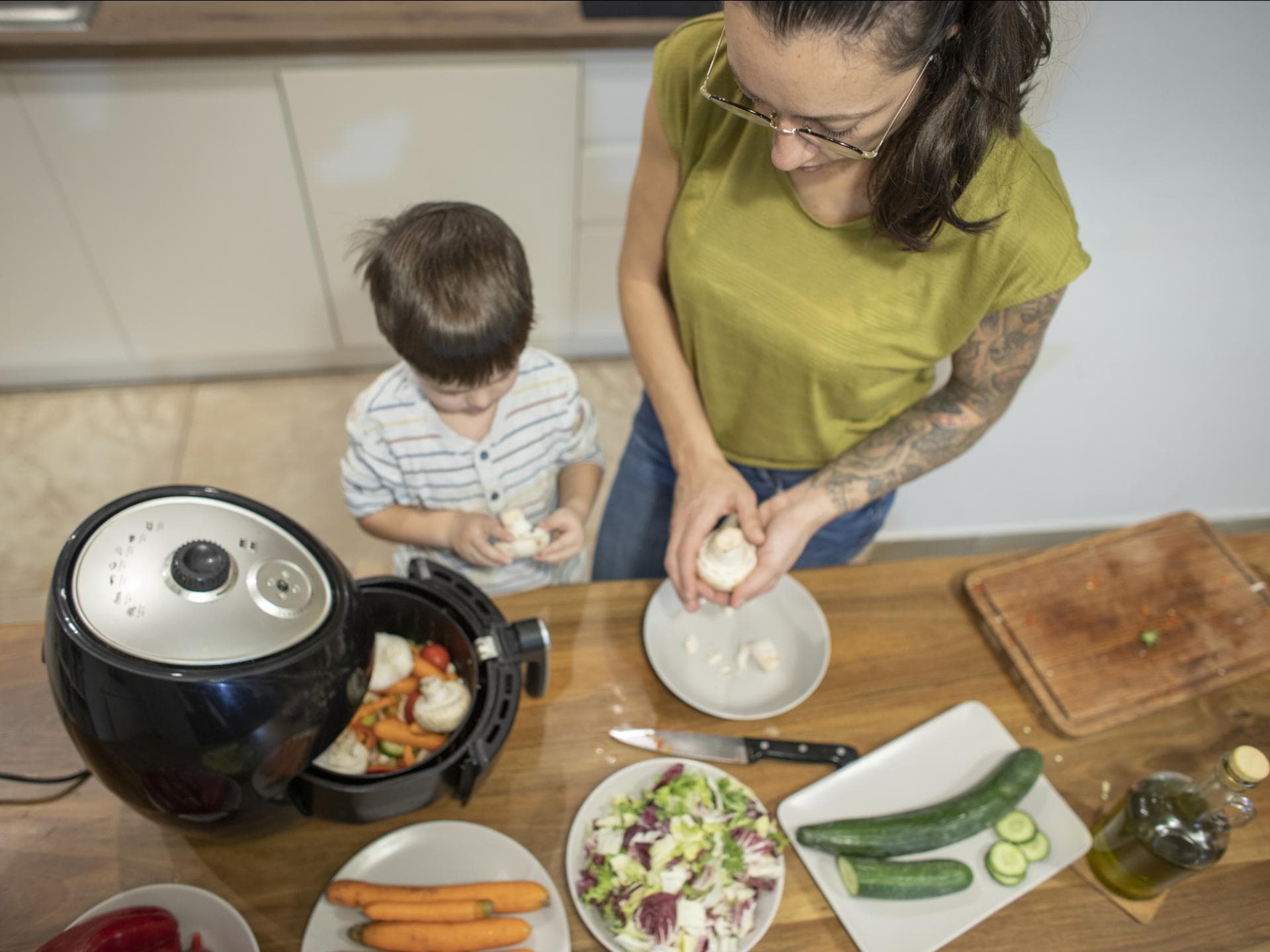 Eine Heißluftfritteuse gart effizient und gesund. Mutter und Kind kochen mit dem Airfryer.