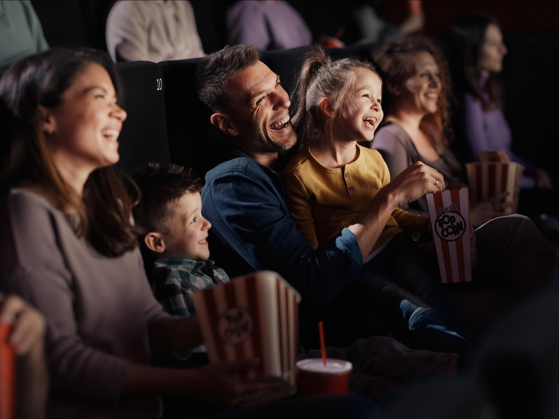Mit der Familie gemeinsam im Kino Spaß haben. Lachende Familie im Kino.