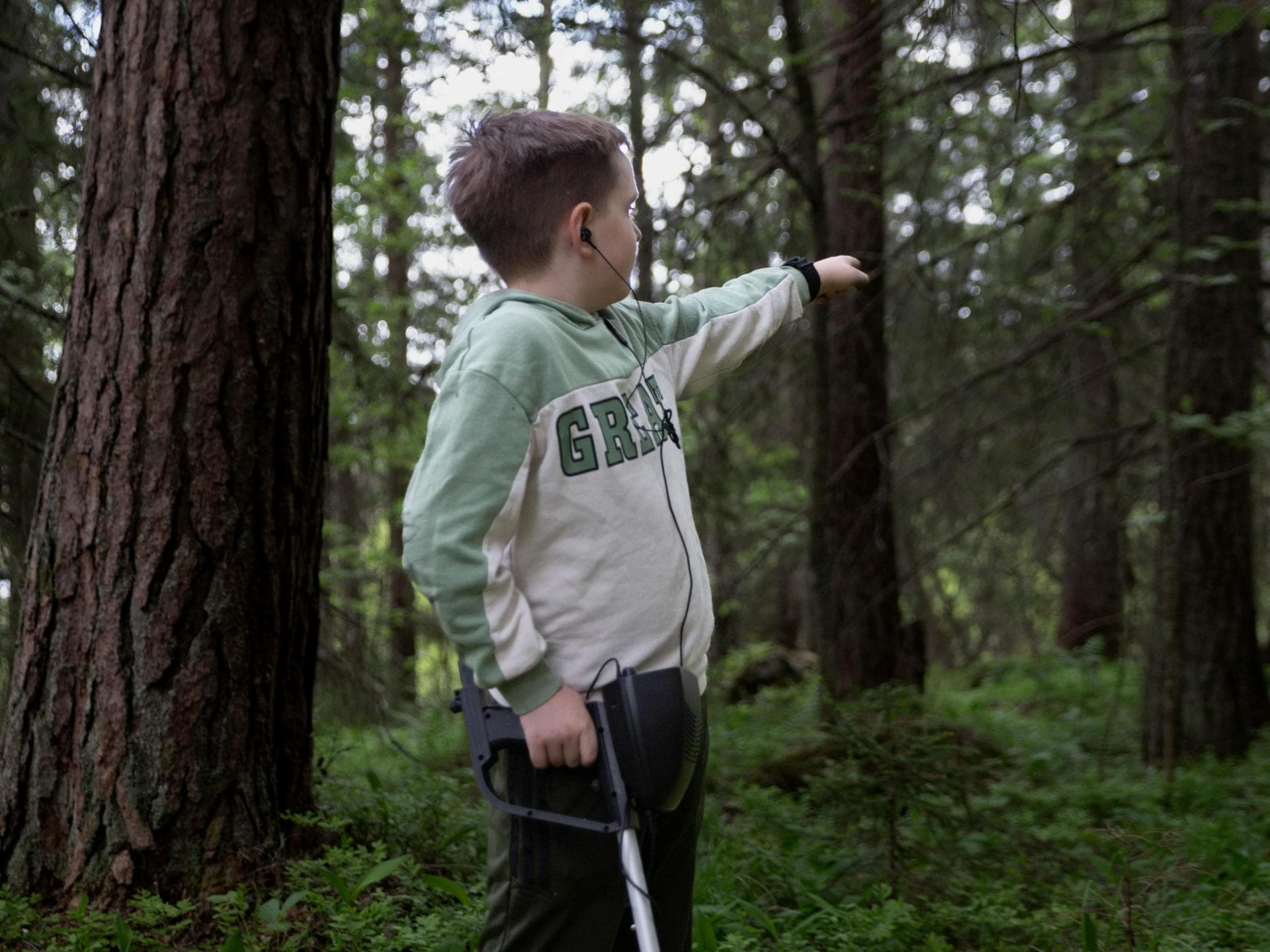 Eine Schatzsuche mit Metalldetektor weckt in Kindern Abenteuerlust. Ein Junge steht mit einem Metalldetektor im Wald.