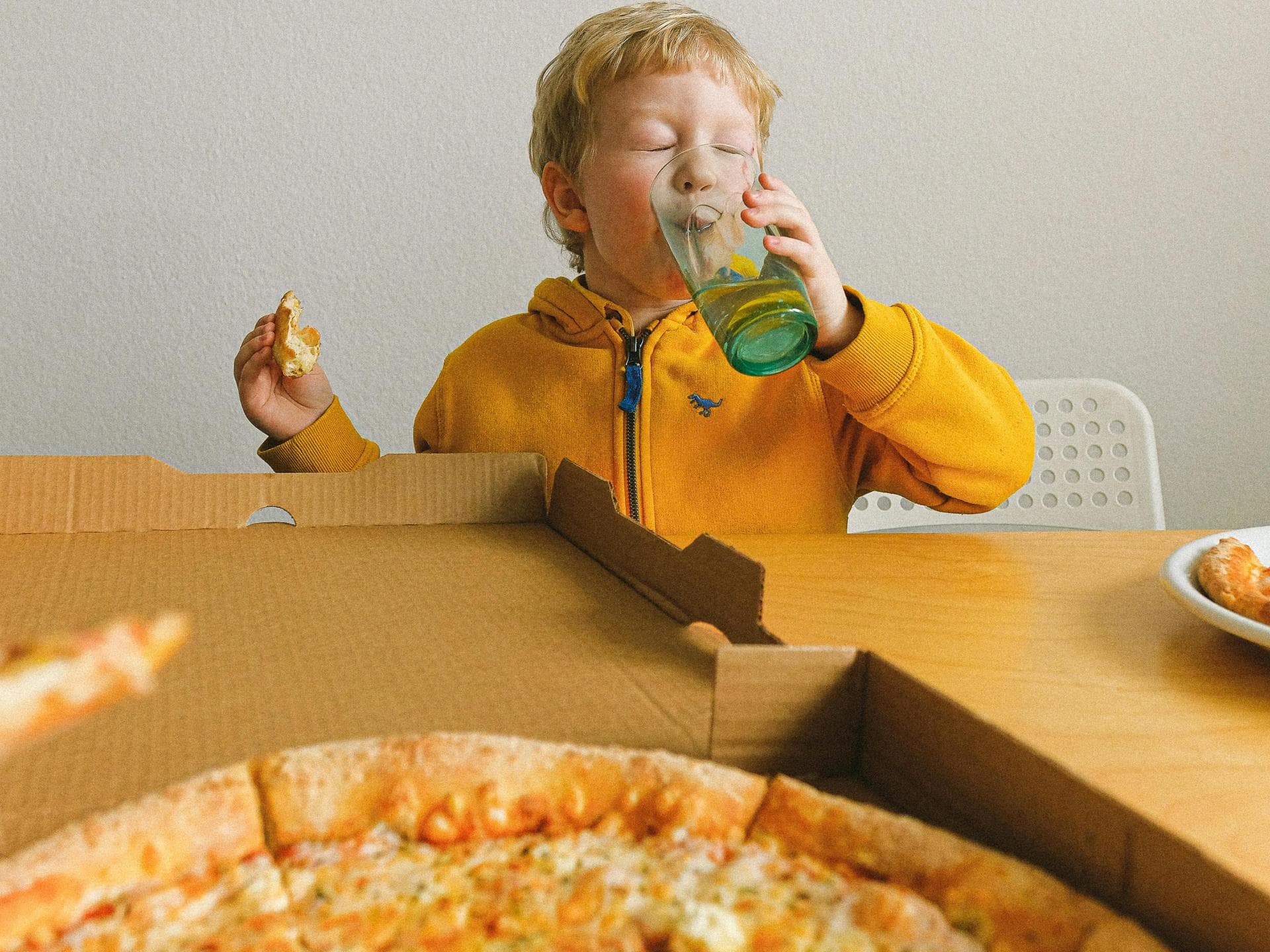 In den meisten Pizza-Kartons steckt Bisphenol A. Kind isst Pizza aus Karton