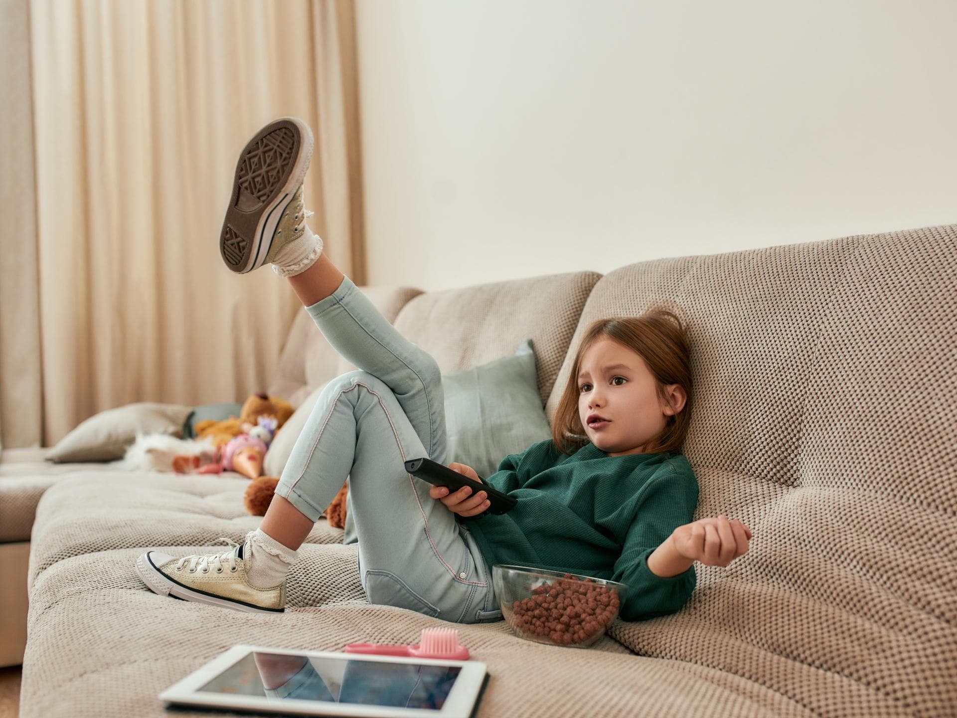 Mädchen auf dem Sofa vorm Fernseher.