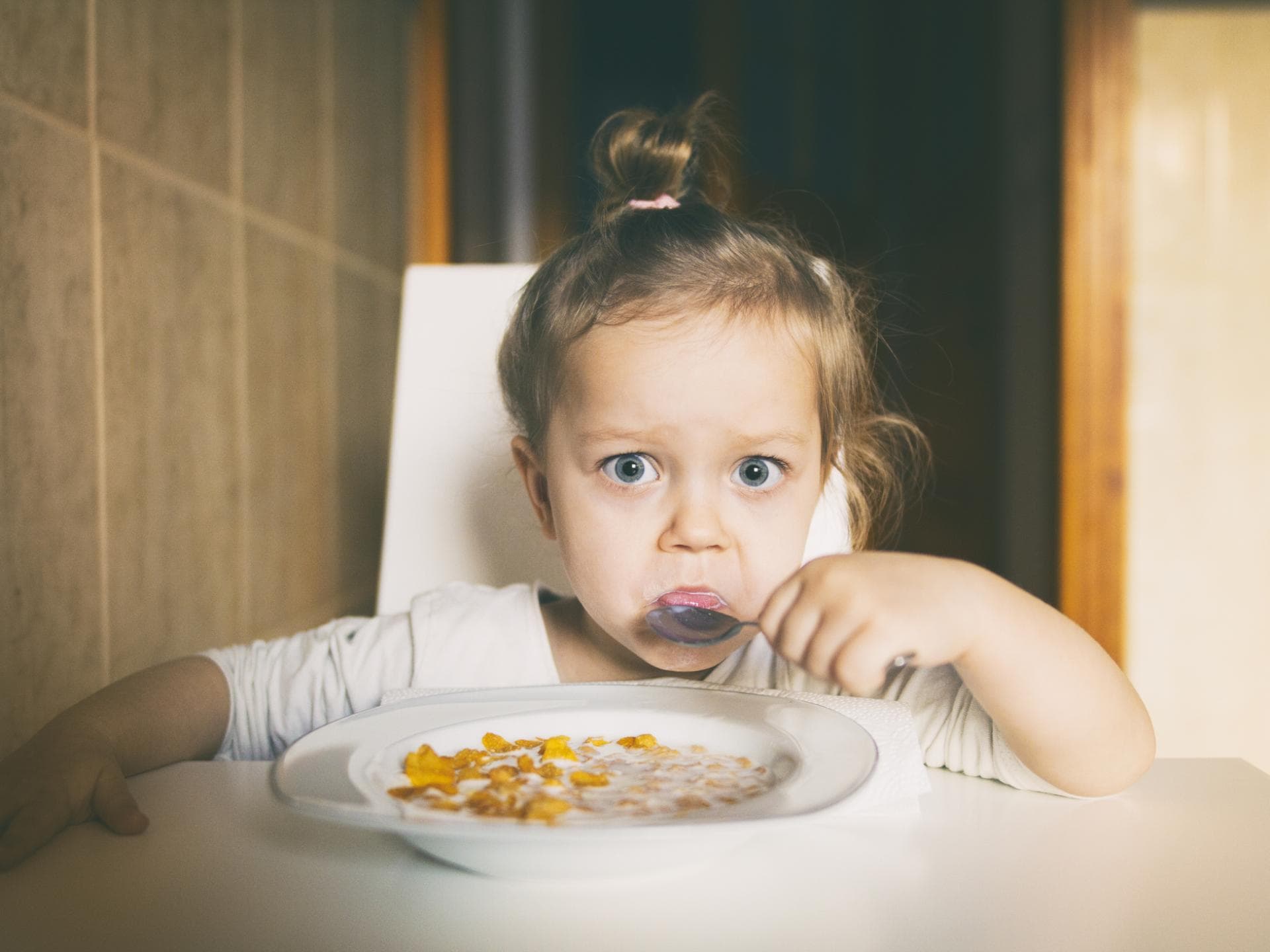 Tischmanieren sind auch für kleine Kinder wichtig. Kleines Mädchen isst Müsli.