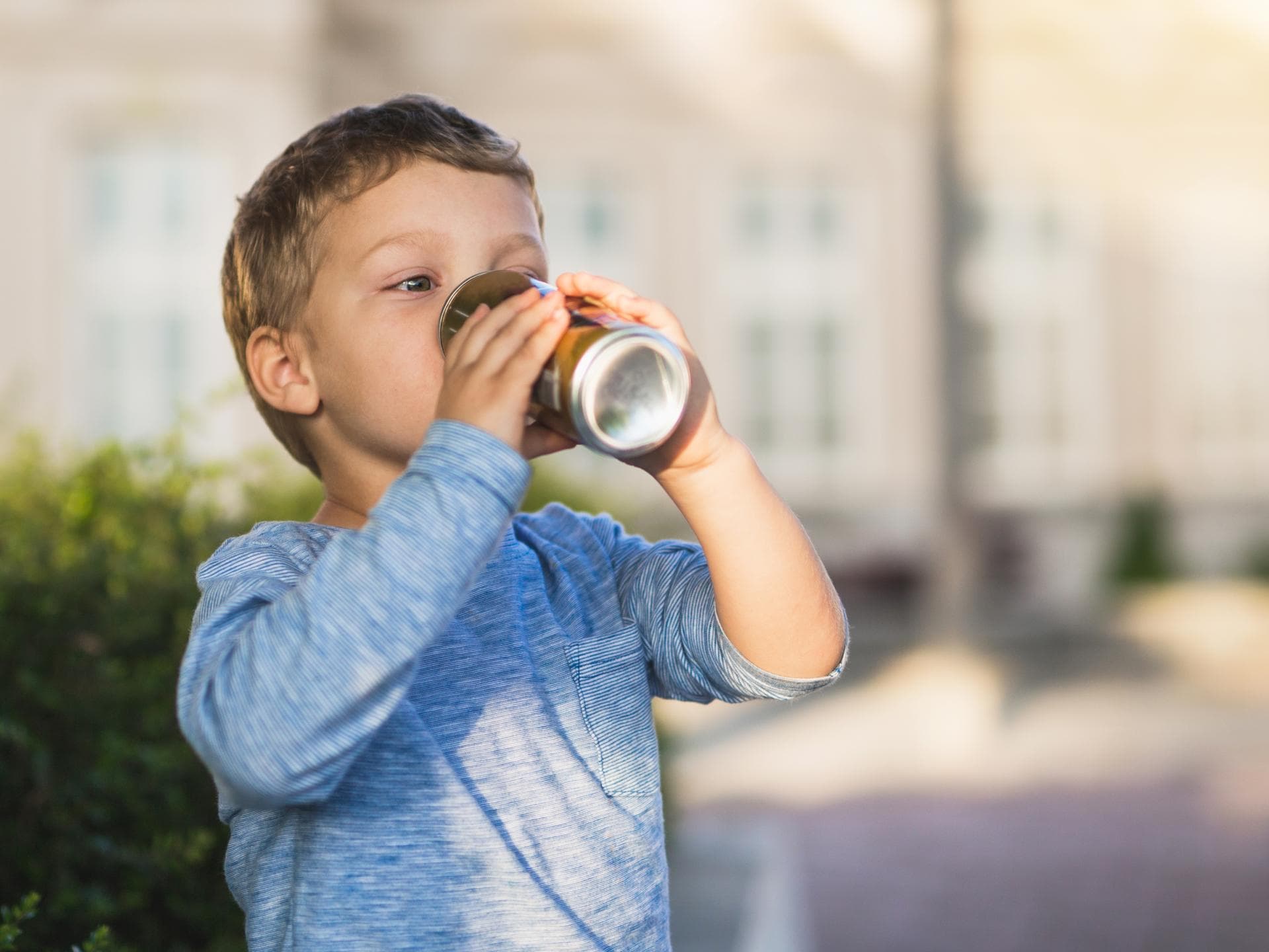 Energy-Drinks stellen für Kinder eine Gefahr dar. Kind trinkt aus einer Dose.