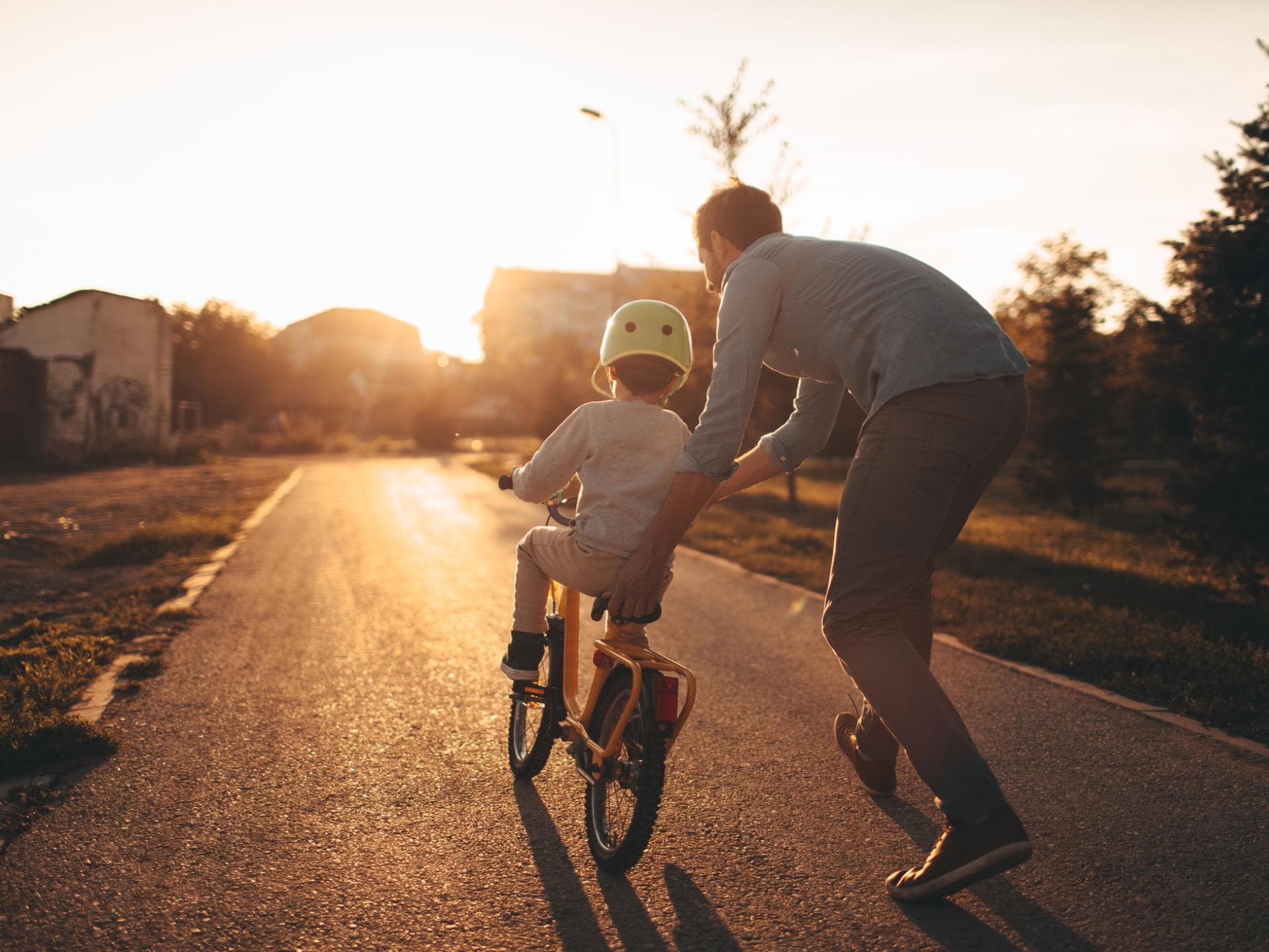 Fahrradfahren will geübt sein. Vater hilft Kind beim Fahrradfahren lernen.