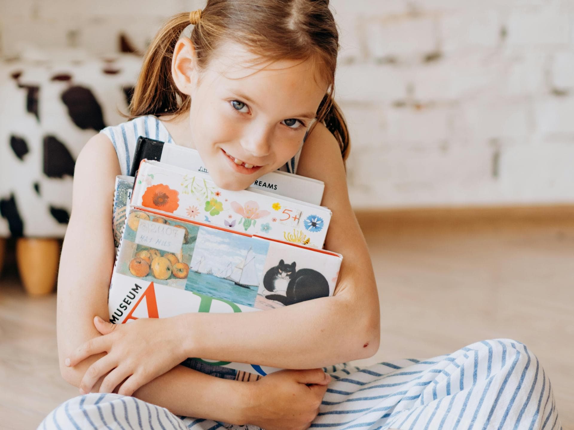 Jedes Jahr werden die schönsten Buch-Cover ermittelt – auch unter den Kinderbüchern. Mädchen umarmt Bücher.