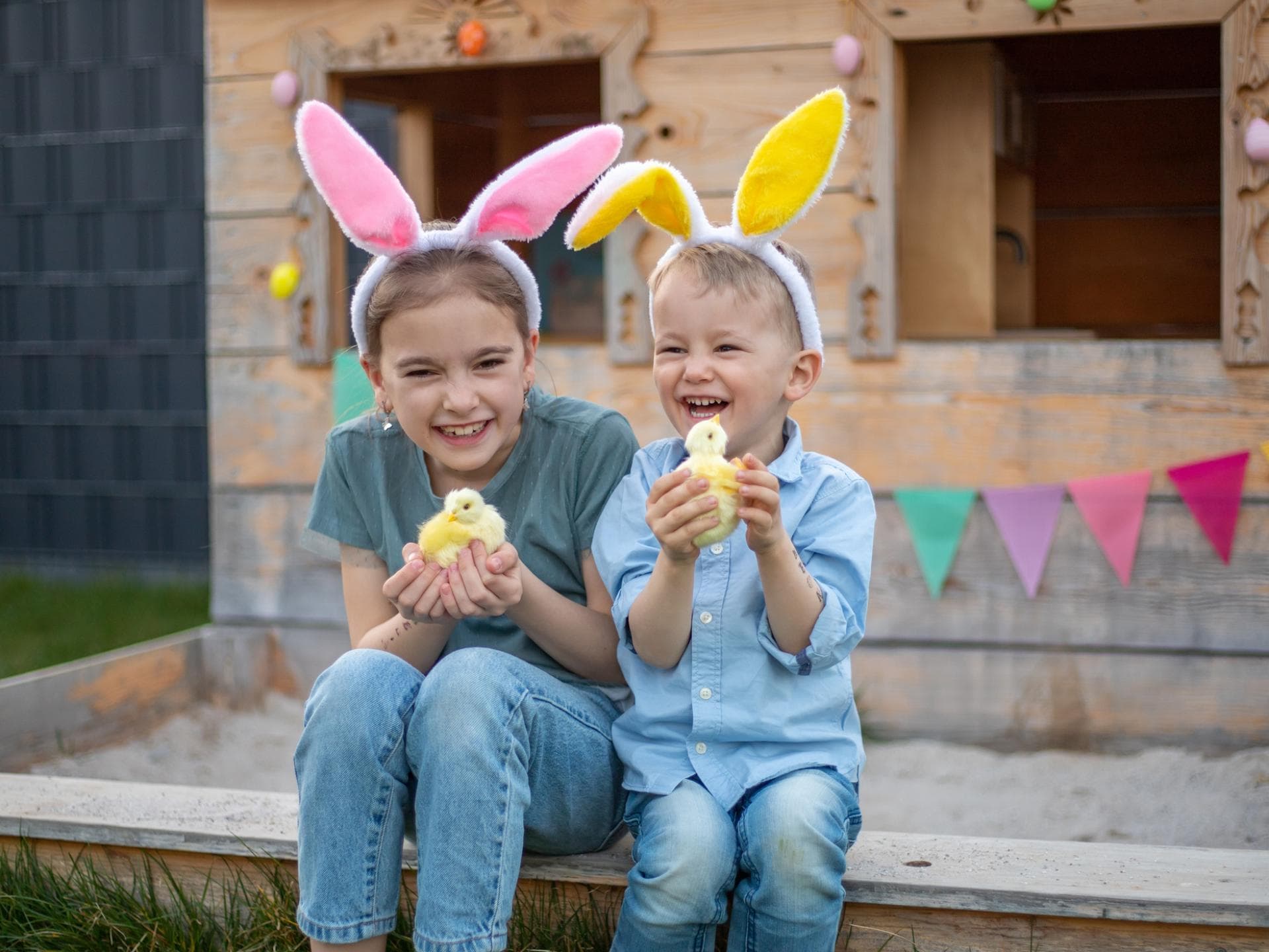 Zwei Kinder mit Osterhasenohren und einem Küken in der Hand