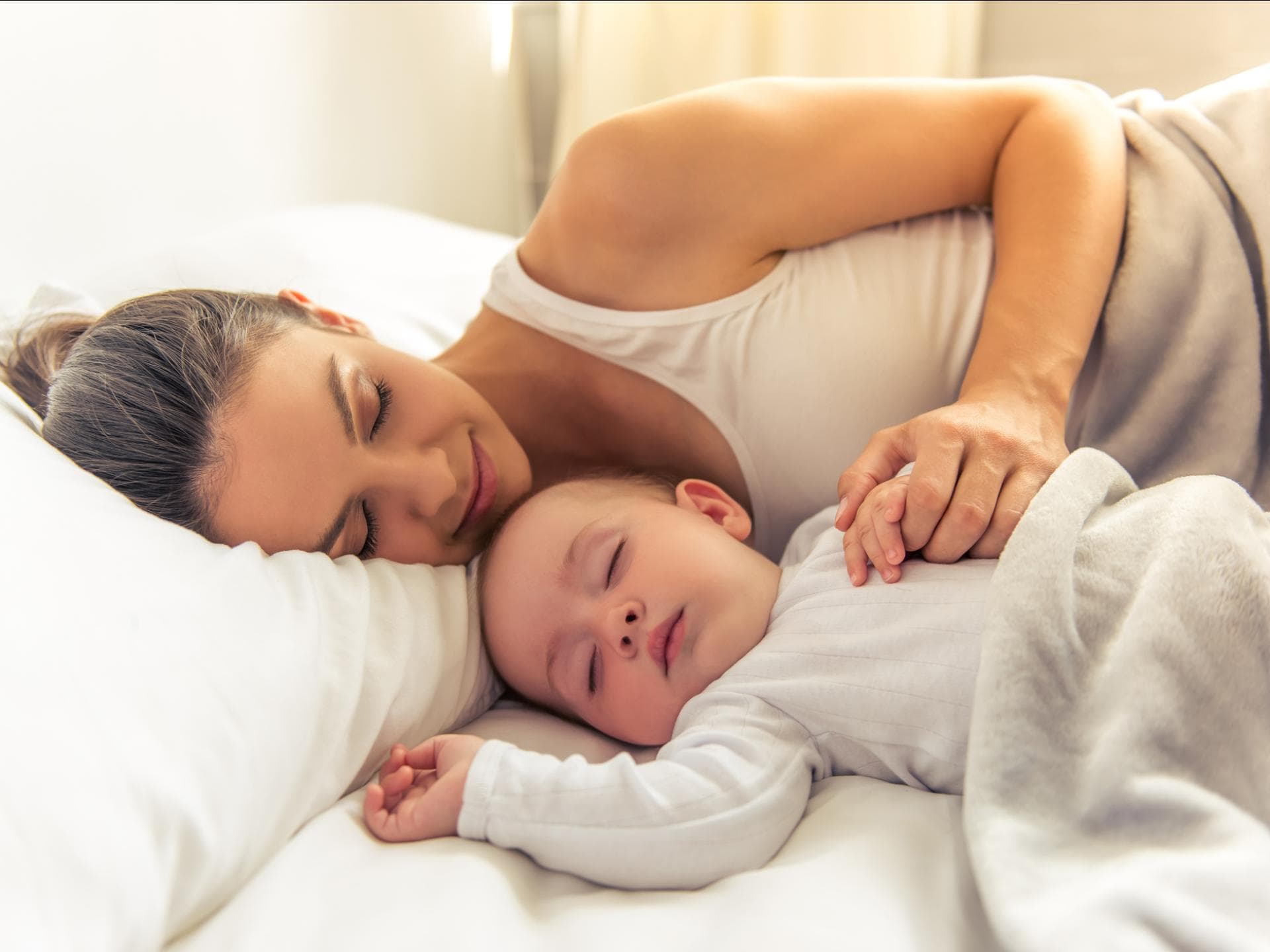 Baby und Mutter schlafen zusammen im Bett.
