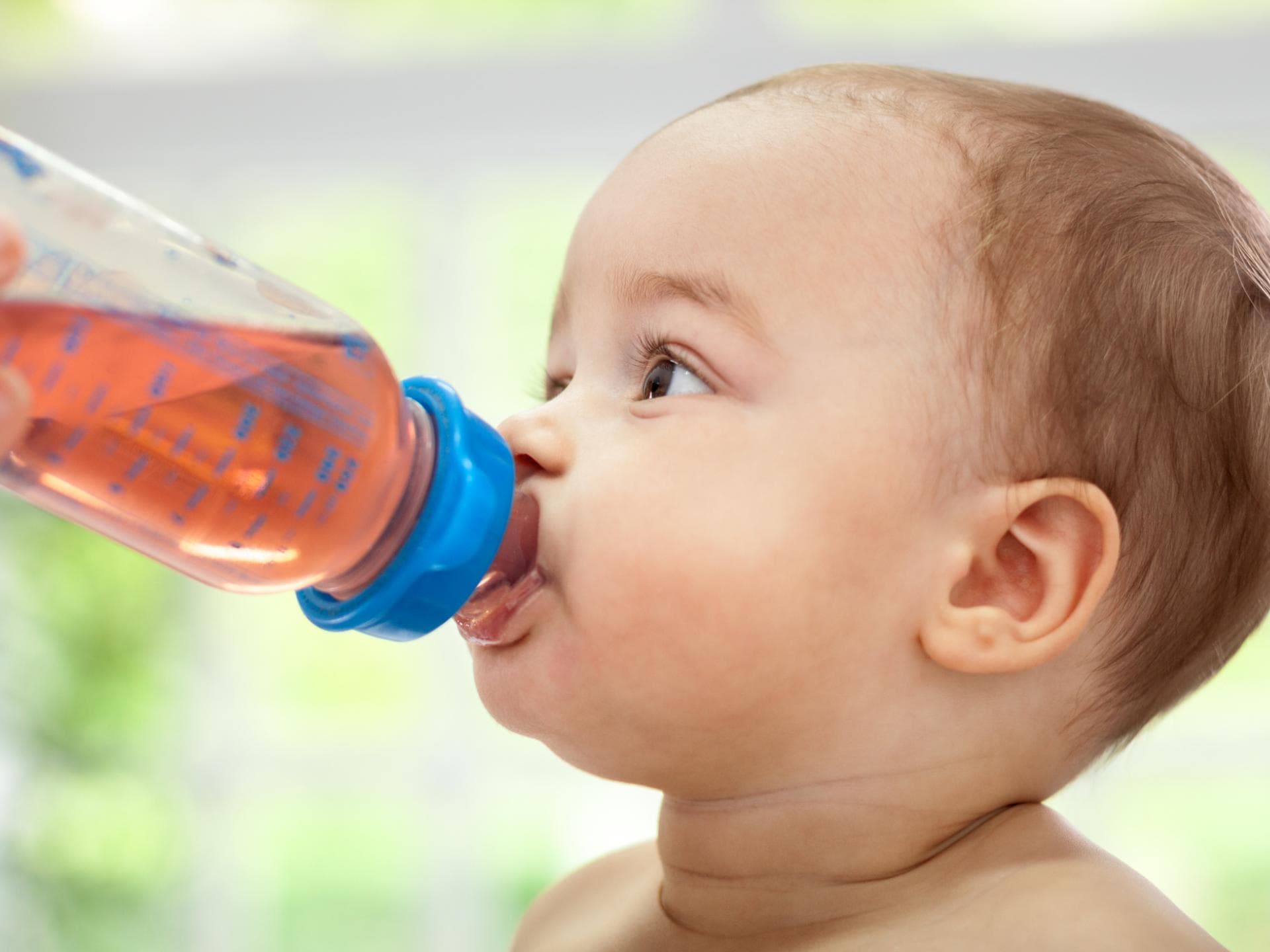 Baby trinkt Tee aus Nuckelflasche.