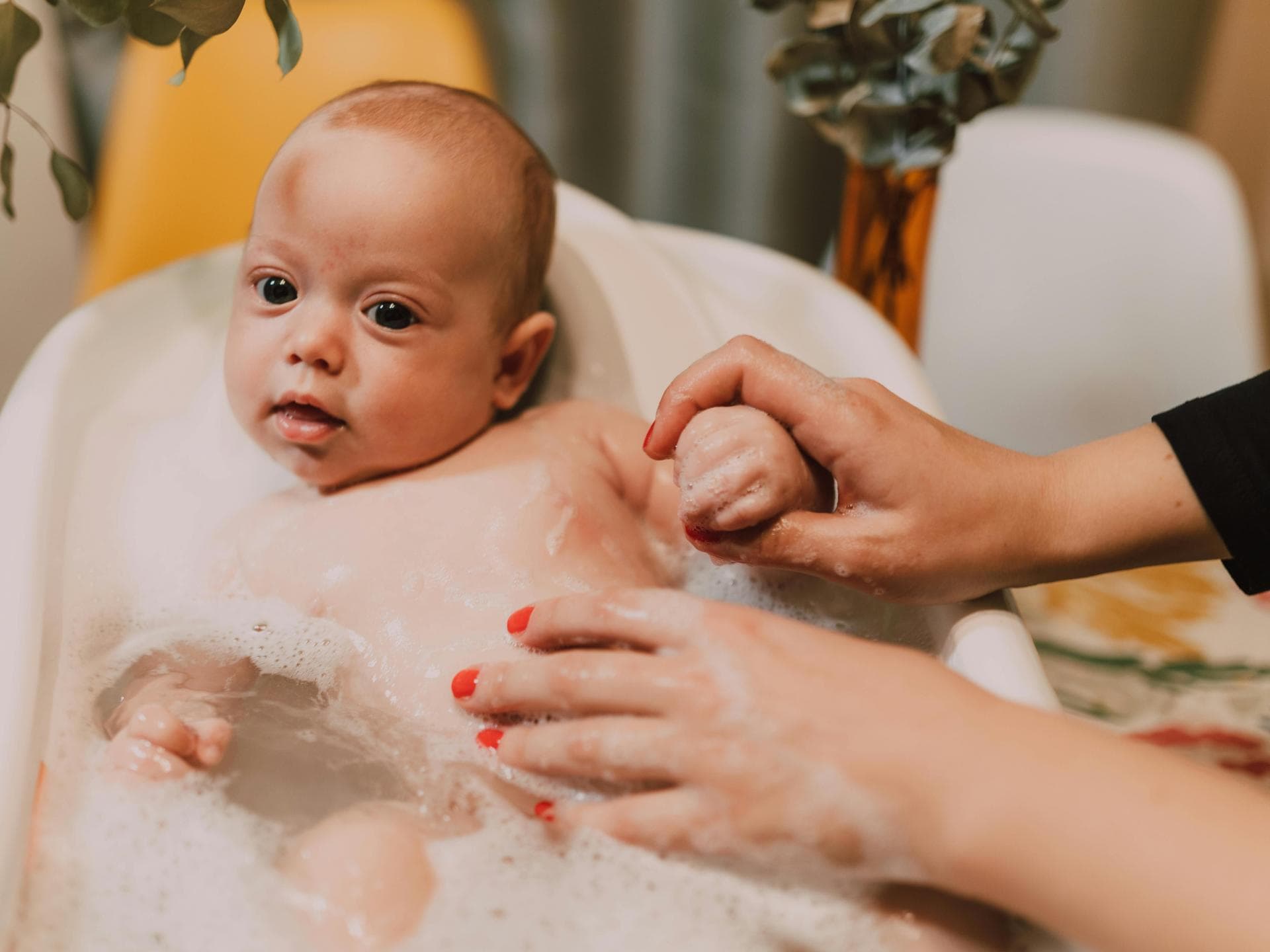 Baby beim Baden. Mutter badet ihr Baby