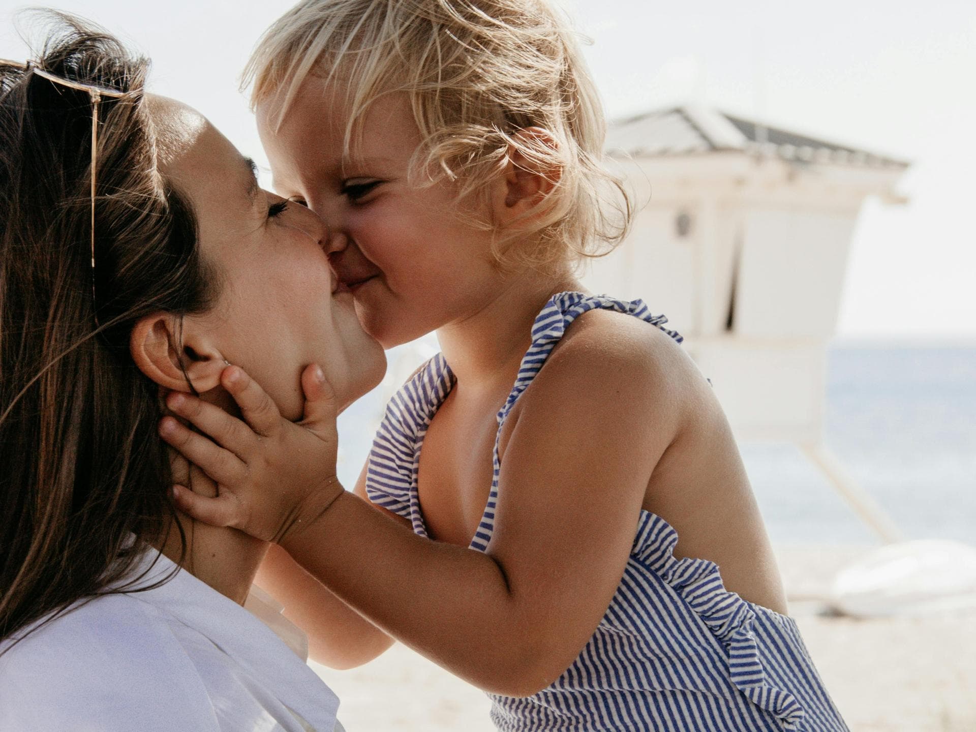 Die Ruhe, die man früher kannte, ist mit Kindern im Urlaub dahin. Kind küsst Mutter am Strand.