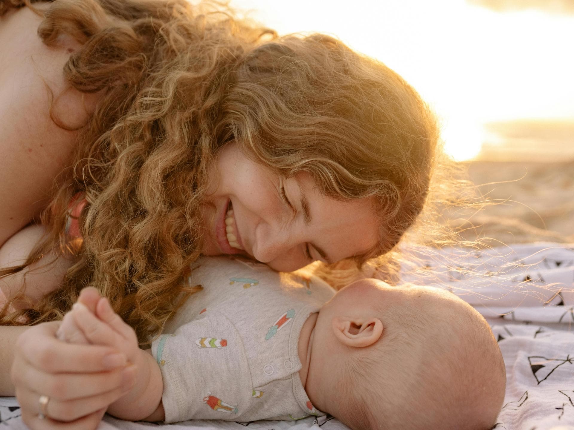 Glückliche Mutter legt am Strand ihren Kopf aufs Baby.