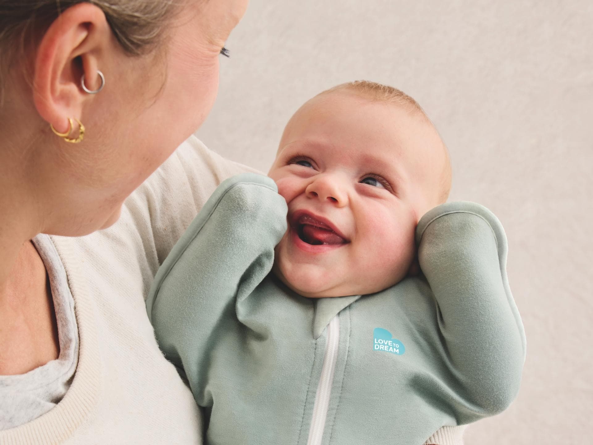 In diesem Pucksack hält Baby die Ärmchen nach oben. Baby im Pucksack auf Mamas Arm.