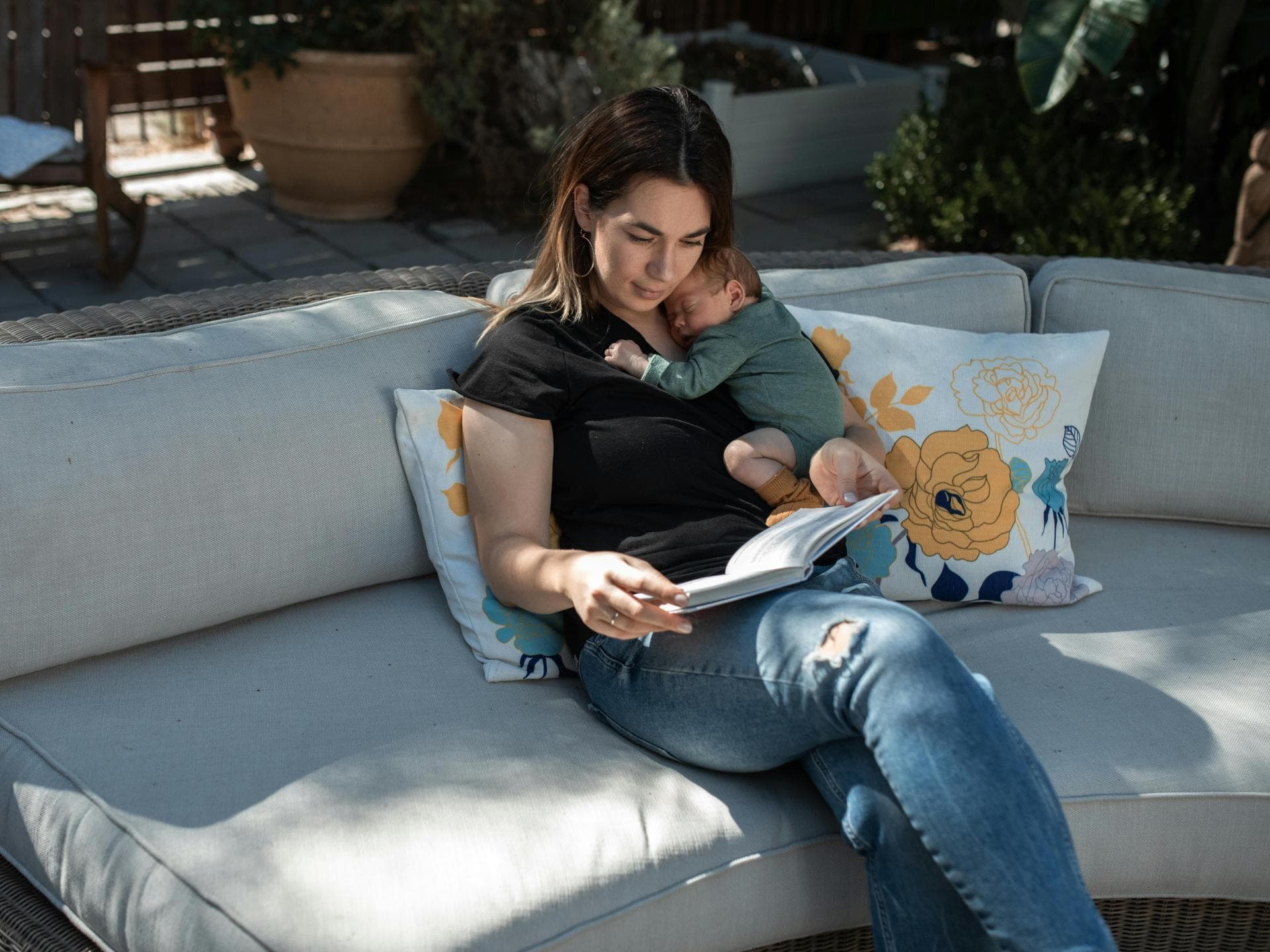 Mama sitzt mit Baby draußen auf Sofa.