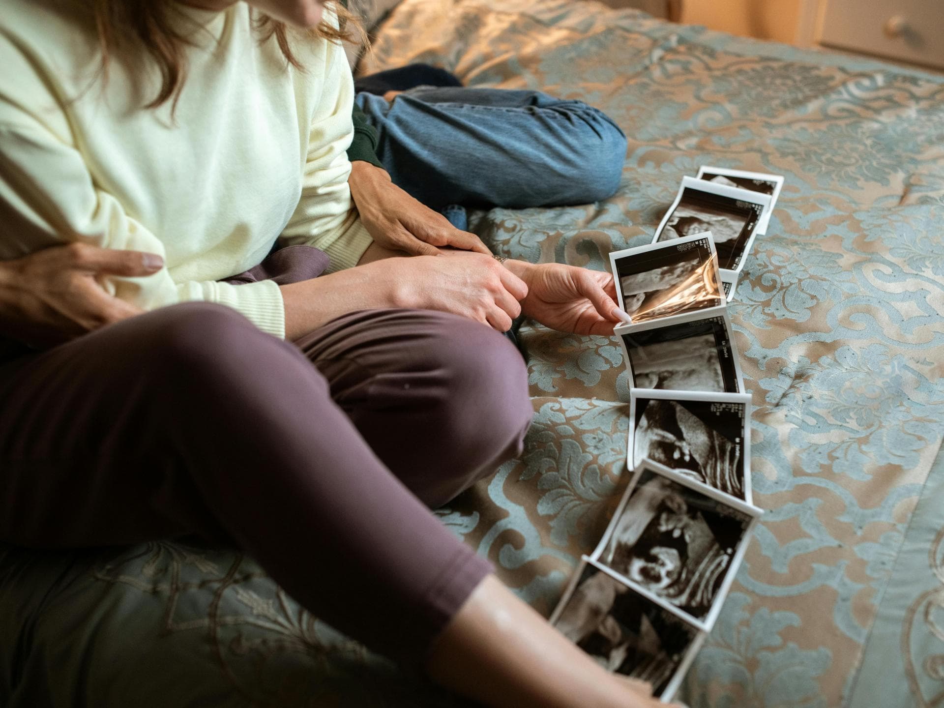 Ultraschallfotos lassen sich wunderbar auf Meilensteinkarten kleben. Paar schaut sich Ultraschallfotos des Ungeborenen an.