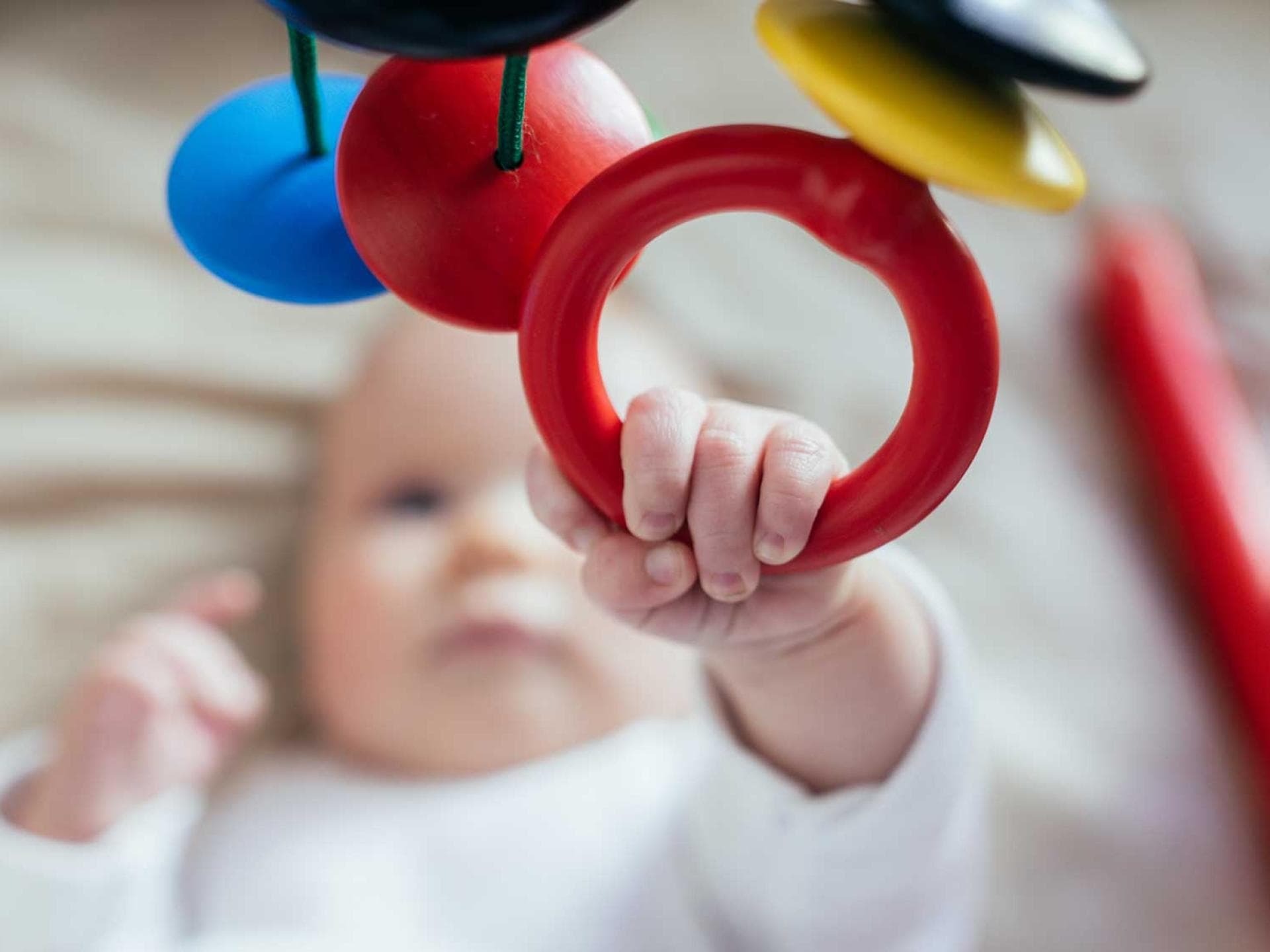 Greif mich mal! Ein Mobile lässt Babys erste Sinne erwachen. Baby greift nach einem Mobile.