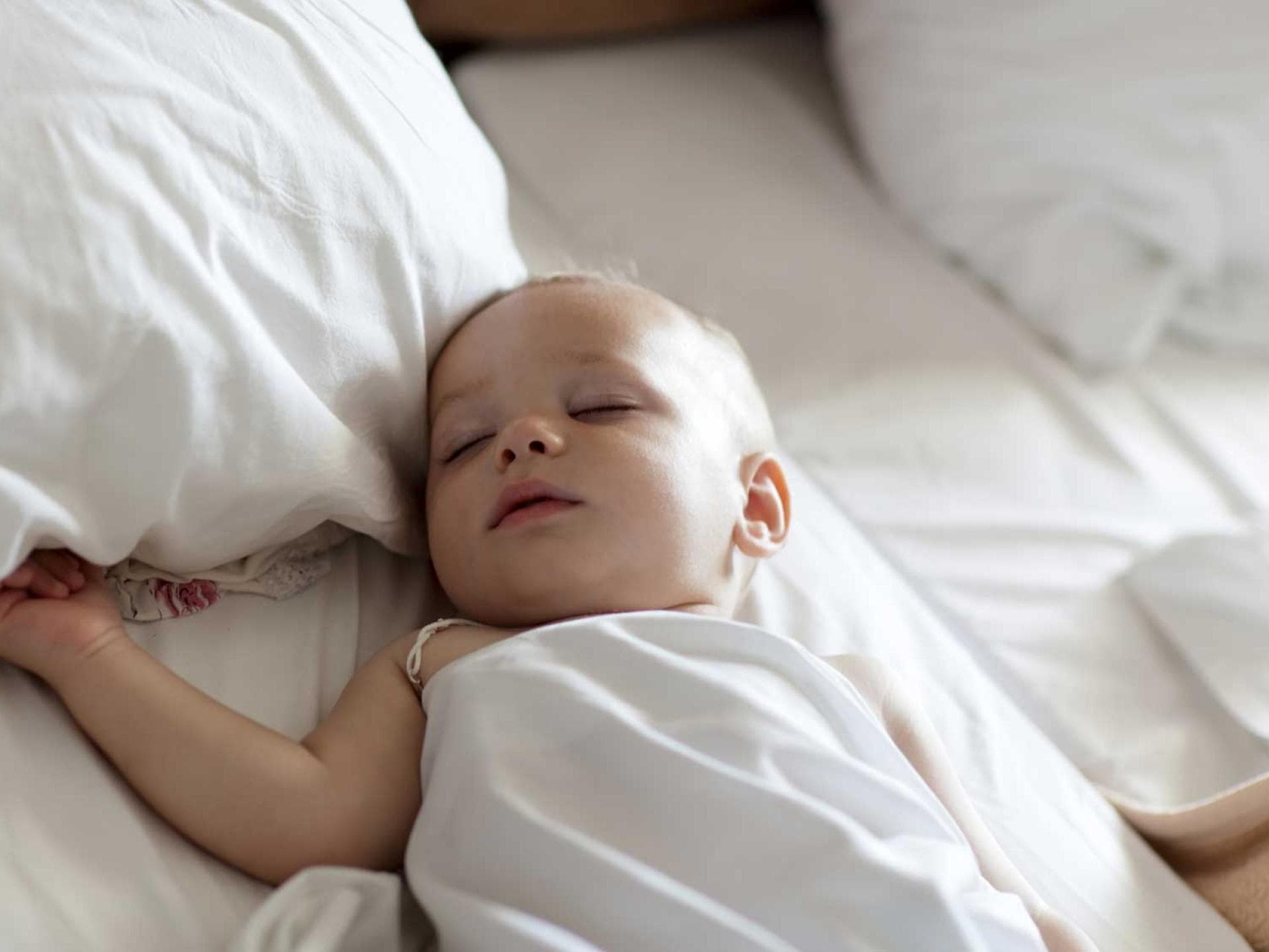 Baby schläft in einem Bett mit großen Kissen.