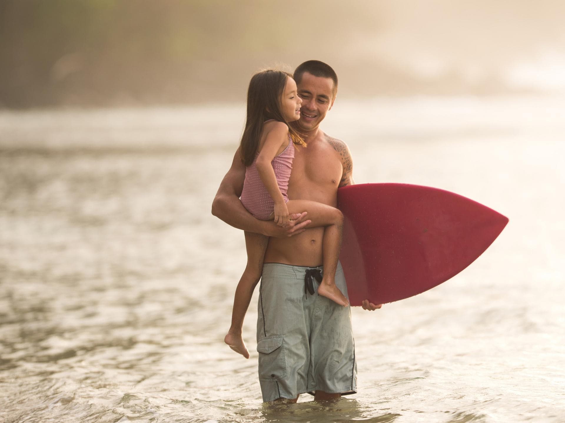 Ein Hawaiianer geht mit seiner Tochter surfen. 