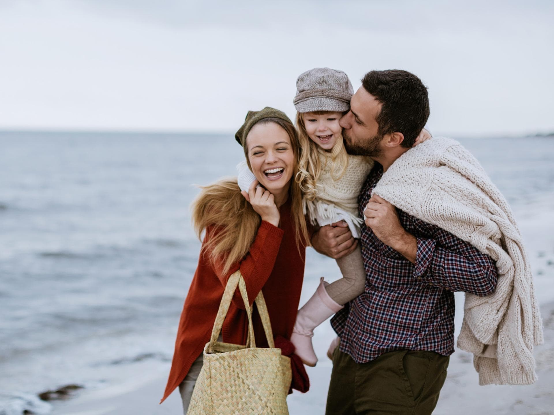Mutter, Vater und Kind gehen am Strand spazieren.
