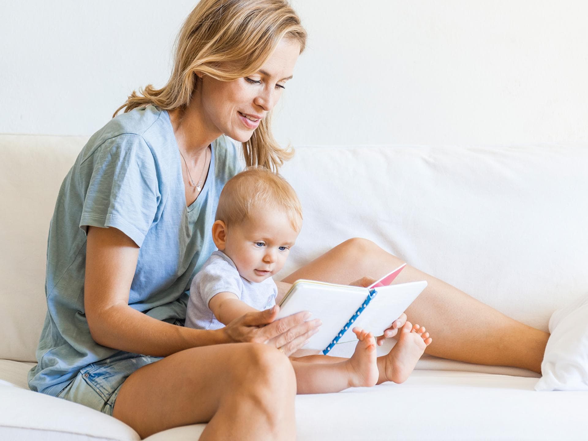 Fühlbücher sind pädagogisch wertvoll und unterstützen die Entwicklung der Babys. Mutter schaut Buch mit Baby an.
