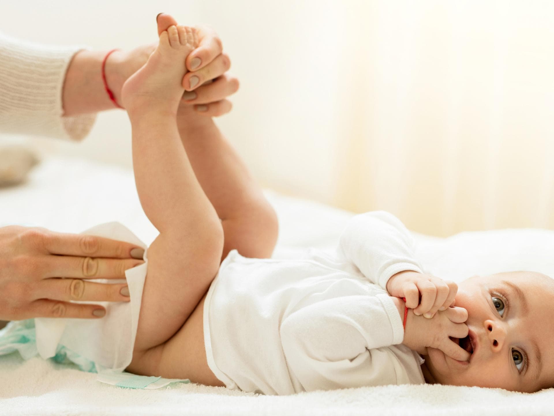 Eine Mutter wechselt ihrem Baby die Windel. 