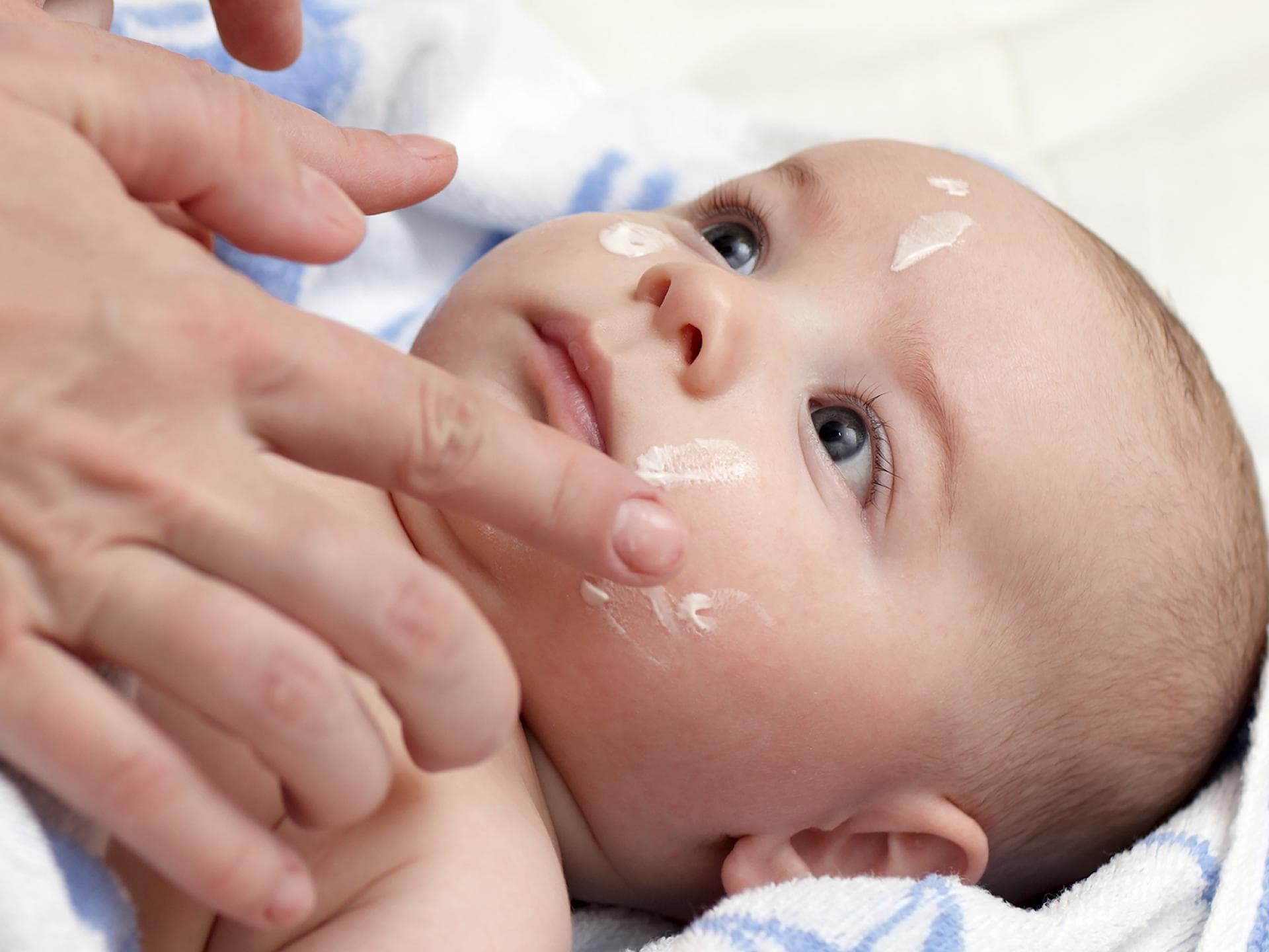 Babys Gesicht wird eingecremt.