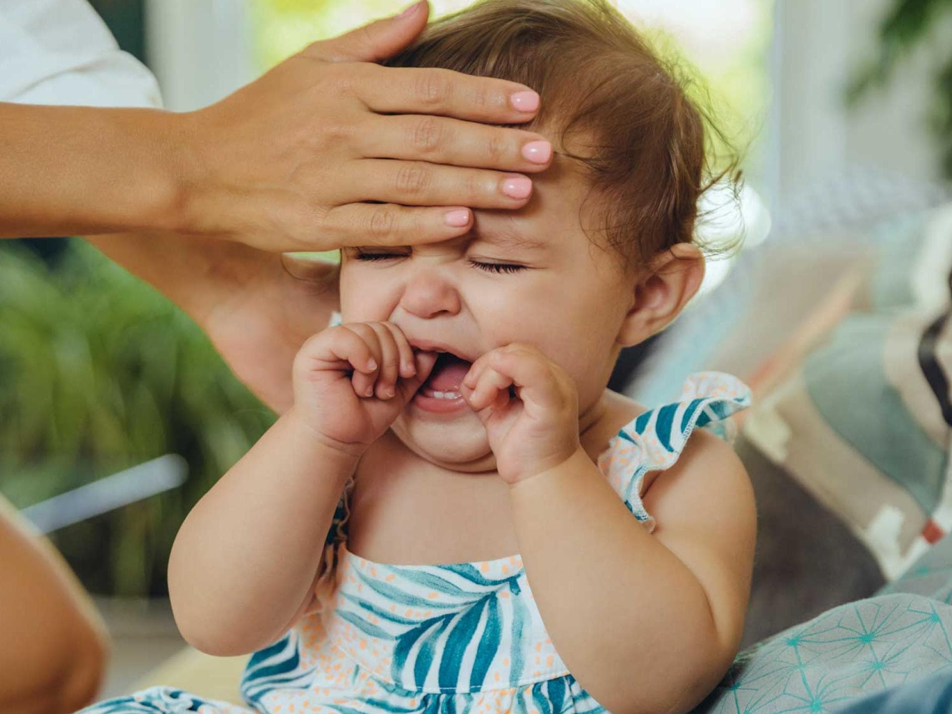 Wenn das Kind nicht mehr aufhört zu schreien und hohes Fieber hat: Ab zum Arzt! Mutter fühlt heiße Stirn eines schreienden Babys.