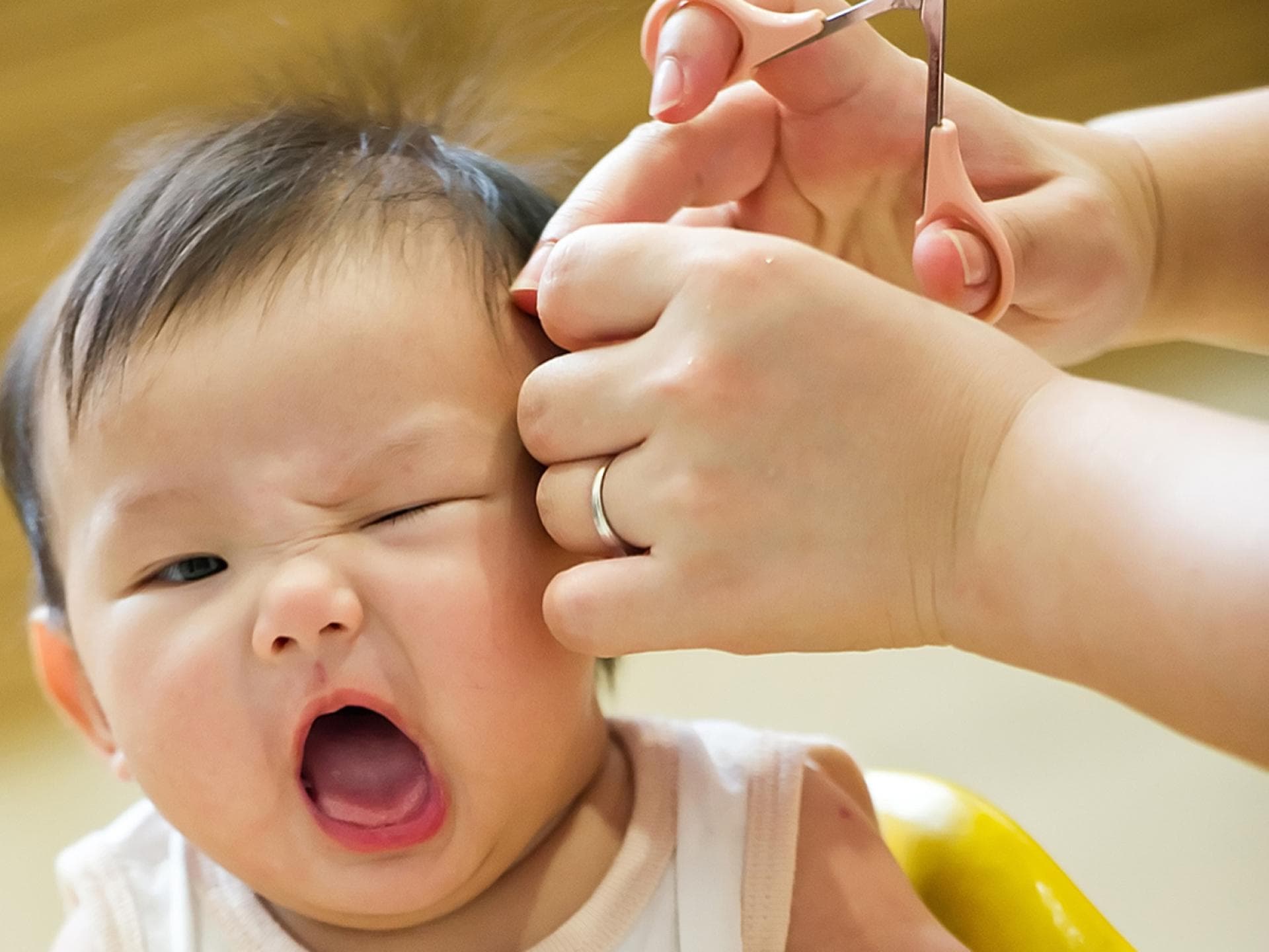 Babys sind nicht immer begeistert, wenn man ihnen die Haare schneiden möchte.