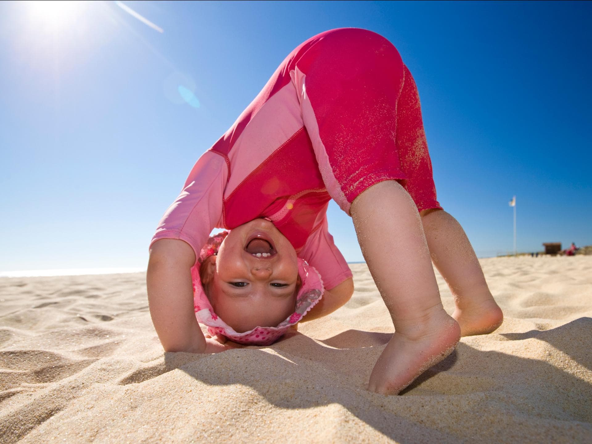 Ein Baby spielt in UV-Kleidung am Strand. 