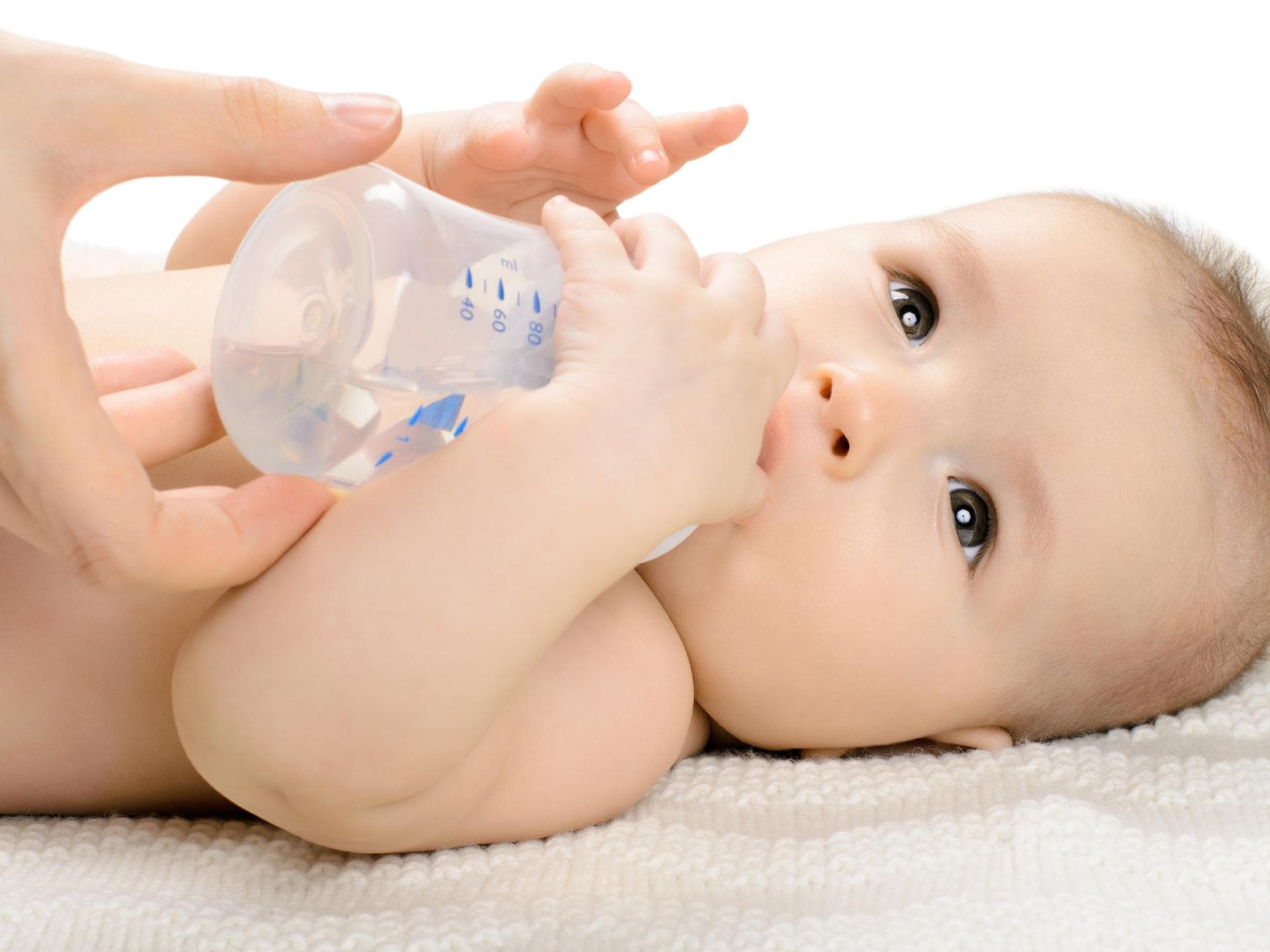 Babys unter sechs Monaten sollten kein Wasser zum Trinken bekommen, um die Gefahr einer Wasservergiftung zu vermeiden. Baby mit Trinkflasche.