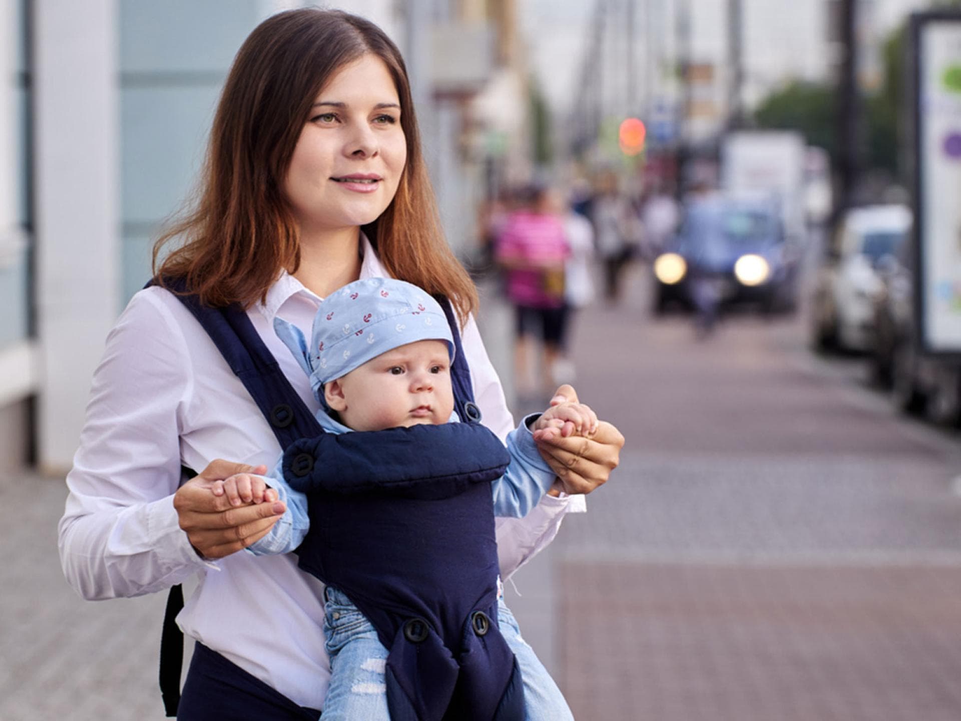 Eine Mutter trägt ihr Baby mit Blick nach vorne in der Trage 