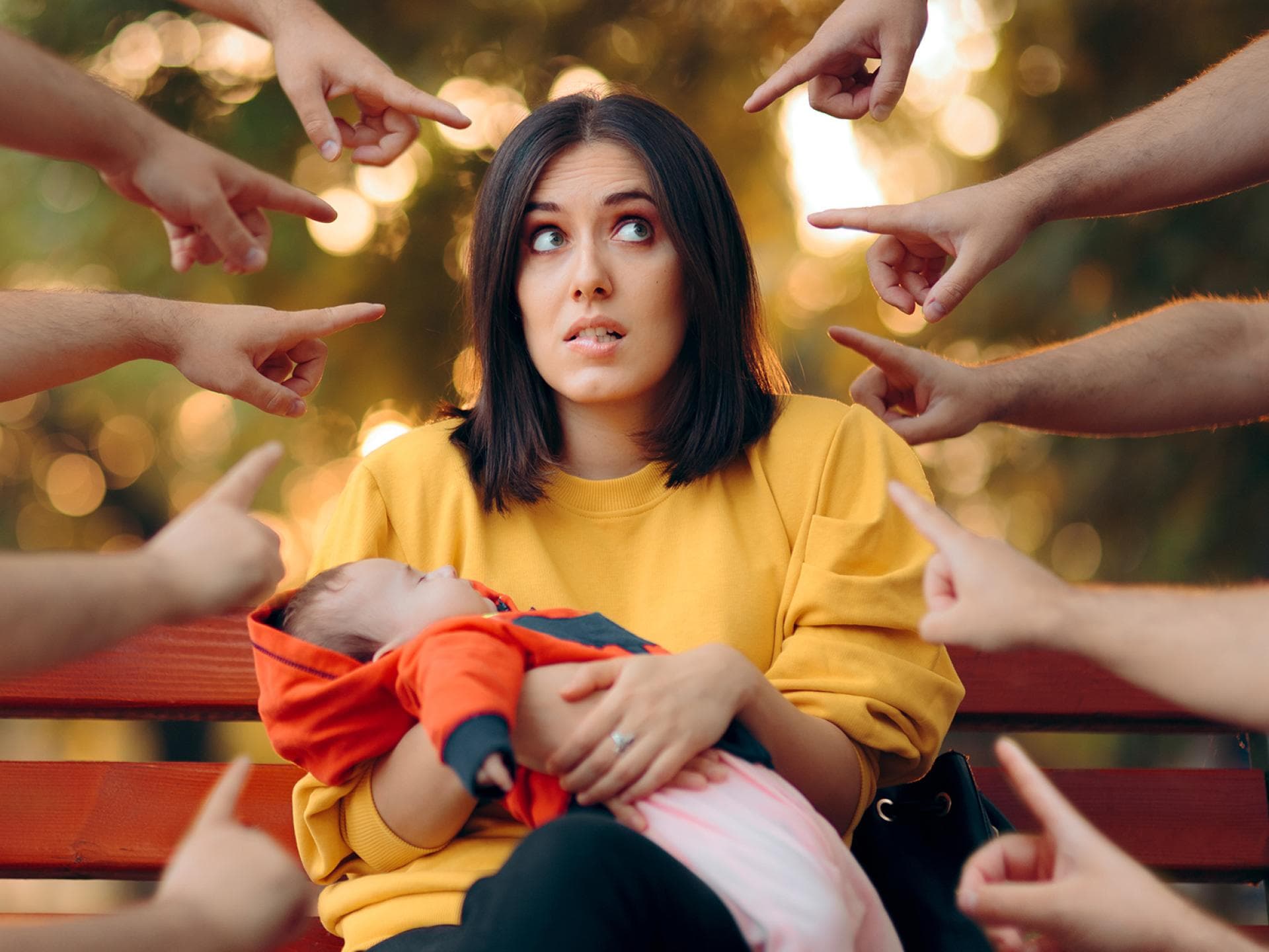 Viele Finger zeigen auf eine Frau mit Baby.