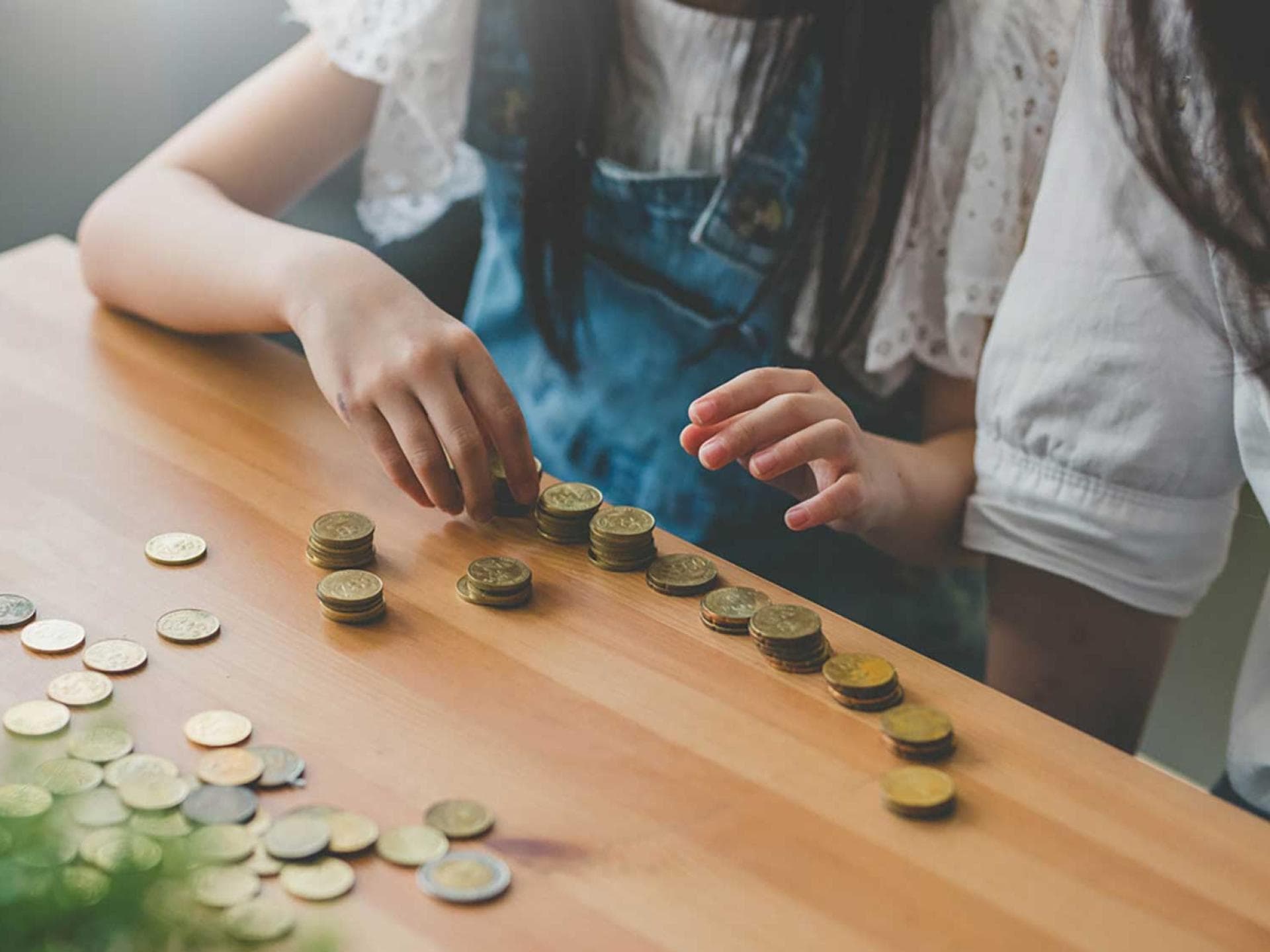 Im Familienleben Geld zu sparen ist gar nicht so schwer – mit den richtigen Tricks. Mädchen zählt Münzen.