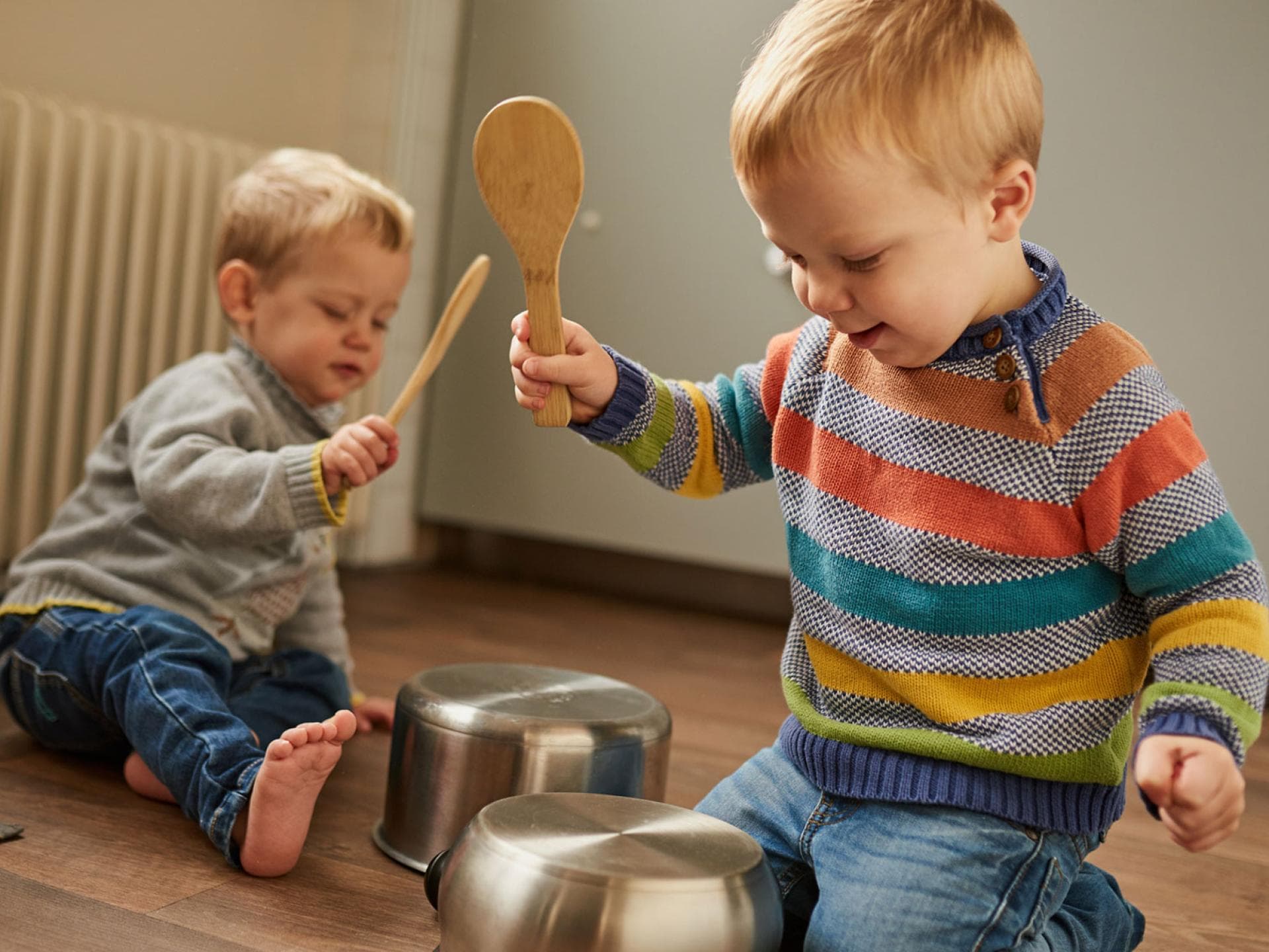Kinder schlagen mit Kochlöffeln auf Töpfe.