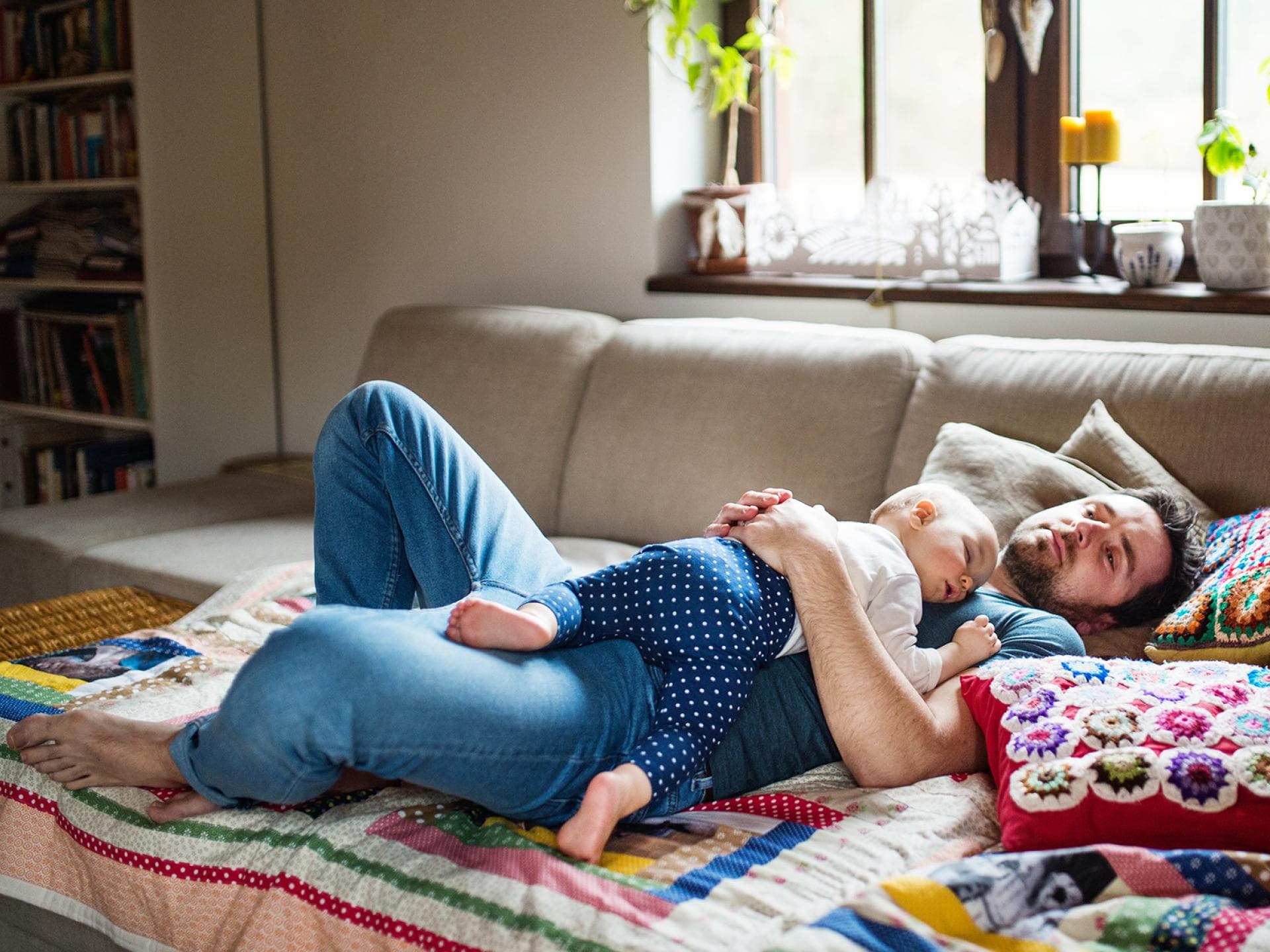 "Ohne Elternzeit wäre meine Bindung zum Kind nicht so eng", glaubt die Hälfte aller Väter, die diese Zeit in Anspruch genommen hat. Baby und Papa liegen schlafend auf dem Sofa.