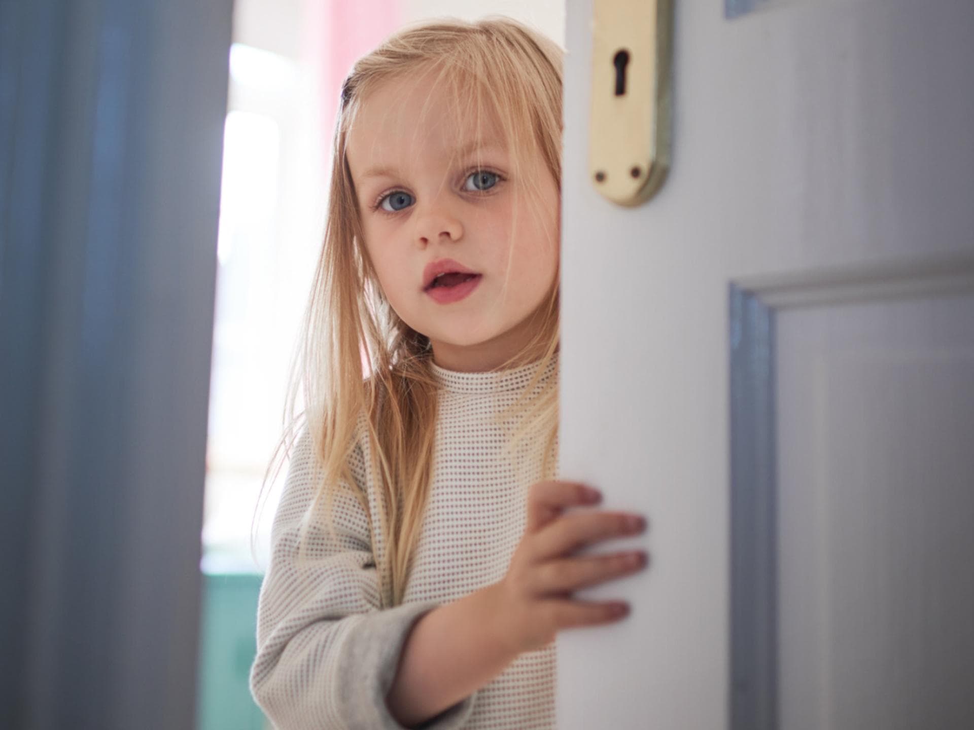Kleines Kind schaut durch die Tür.