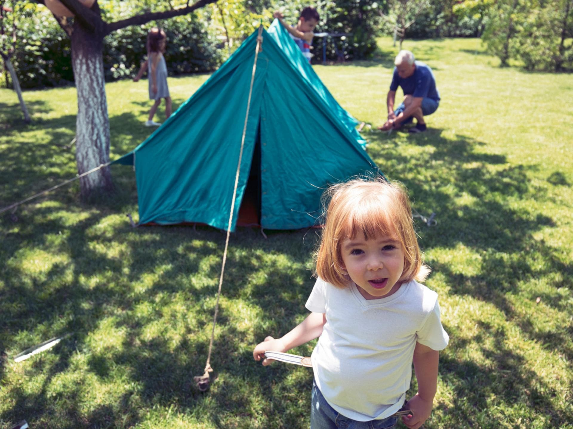 Zelten im Garten ist für Kinder ein tolles Erlebnis. Familie baut ein Zelt im Garten auf.